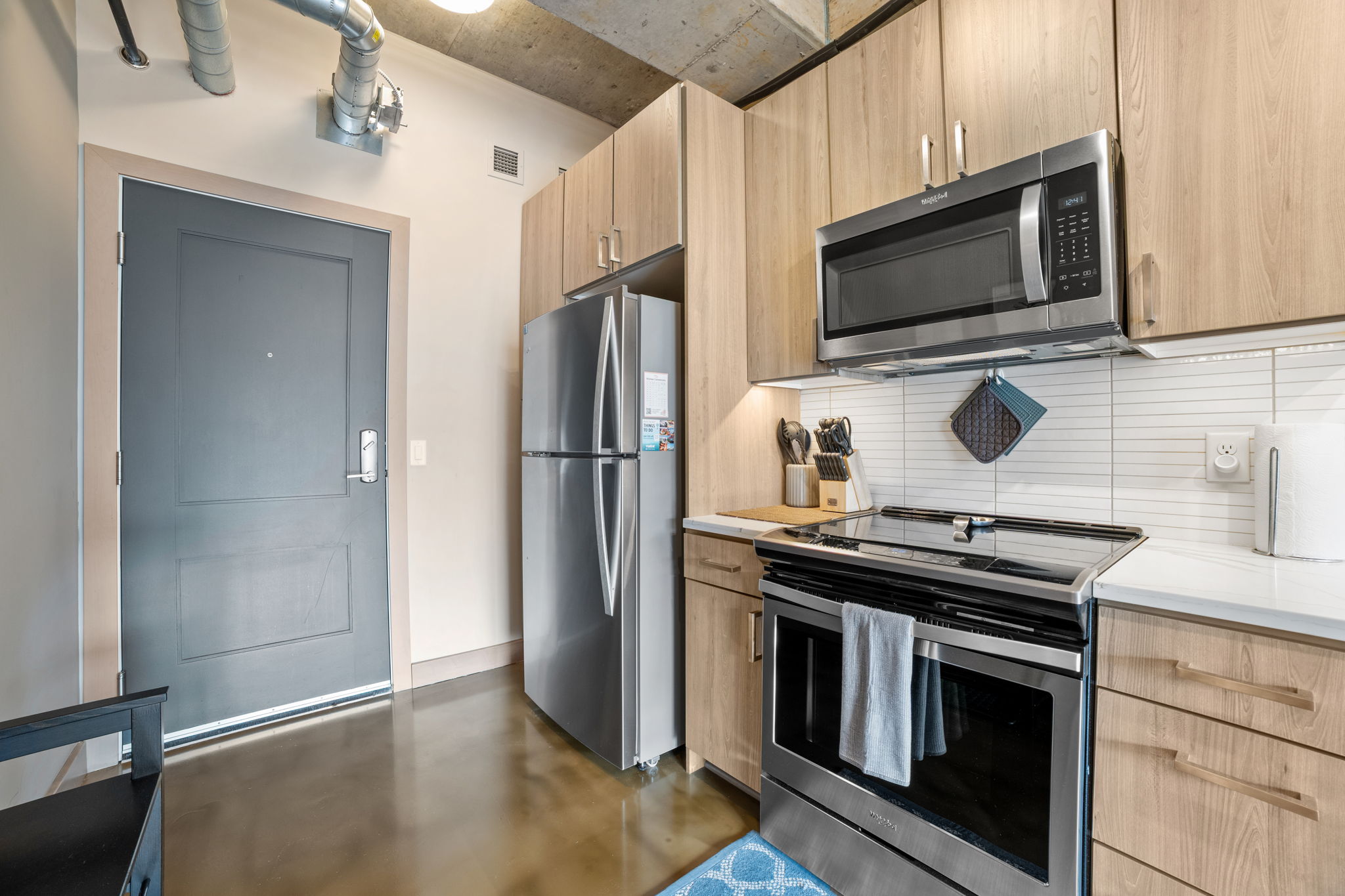 Modern kitchen with sleek appliances and warm wooden cabinetry.
