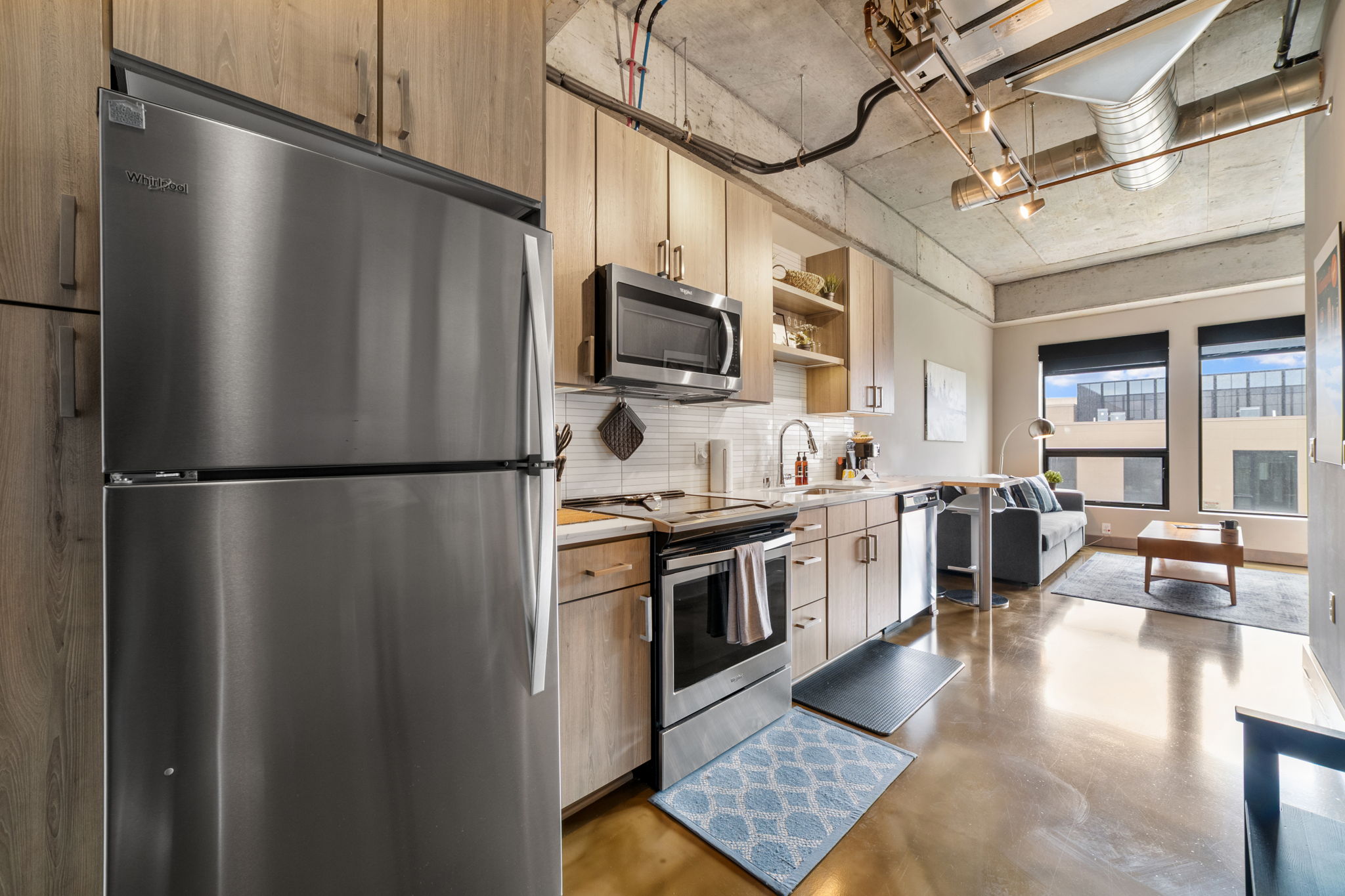 A contemporary kitchen and living area featuring stainless steel appliances and modern decor.