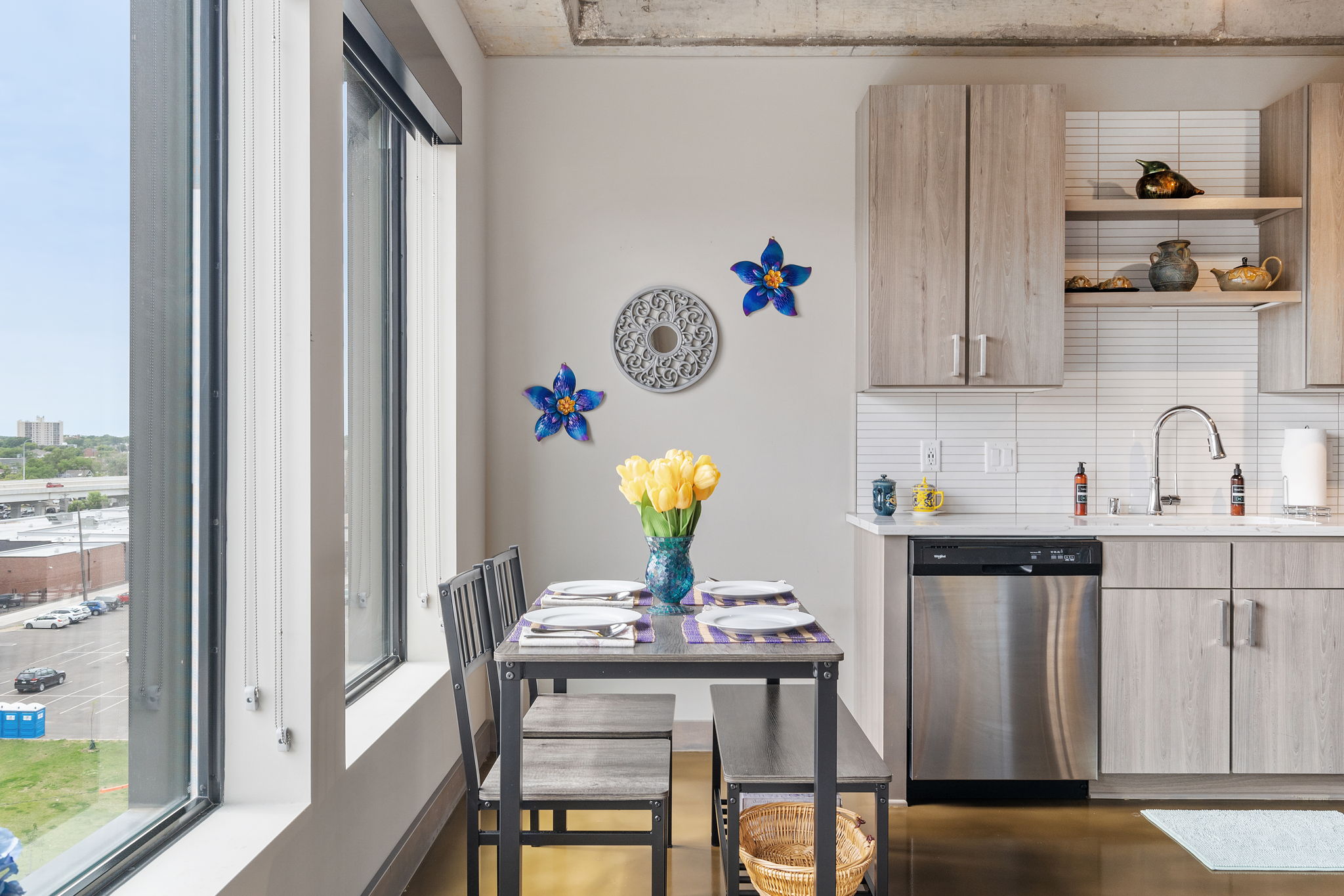 A modern kitchen with natural light, yellow tulips, and vibrant blue flowers.