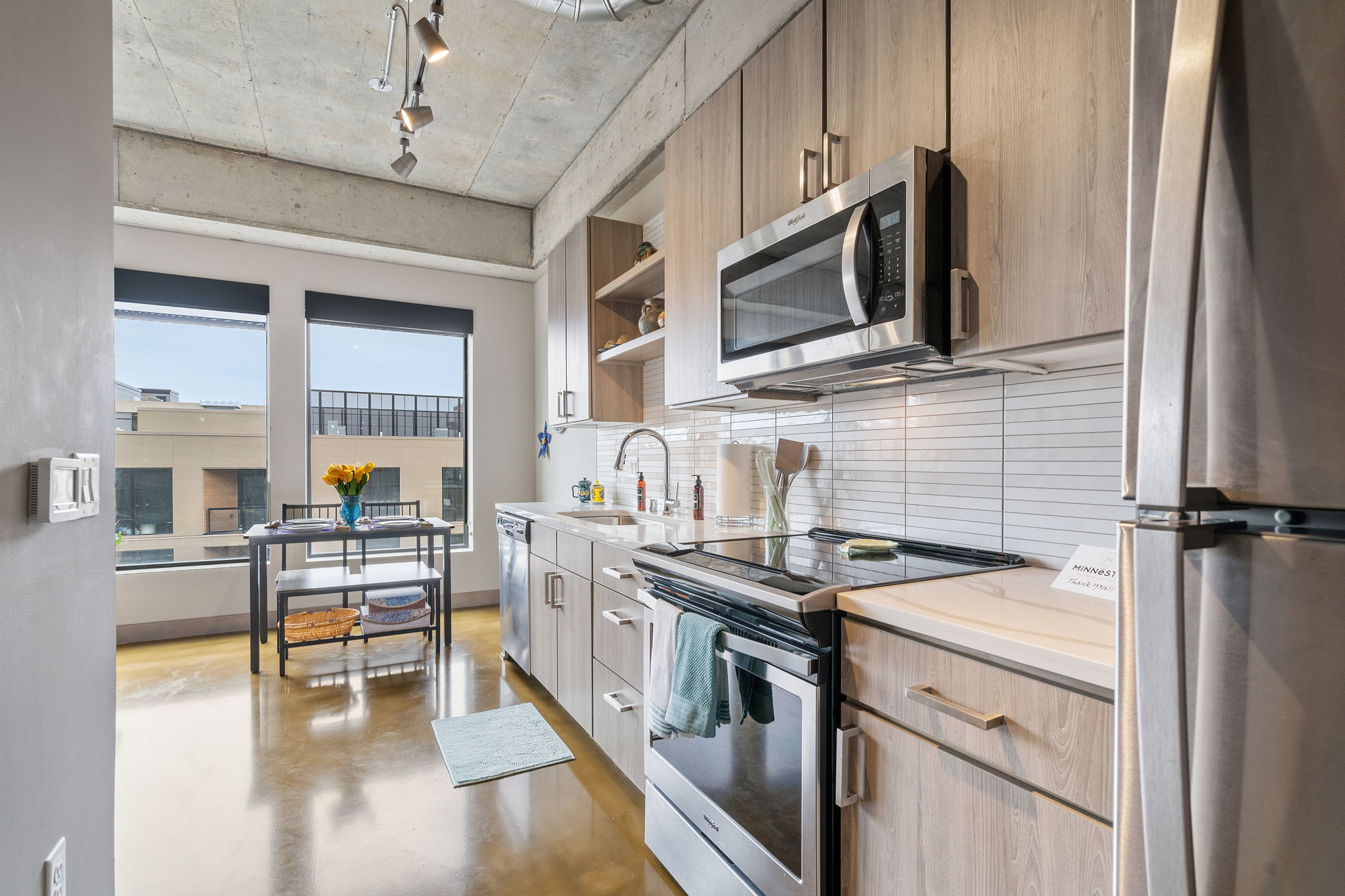A sleek modern kitchen bathed in natural light, featuring stylish appliances and a cheerful floral centerpiece.