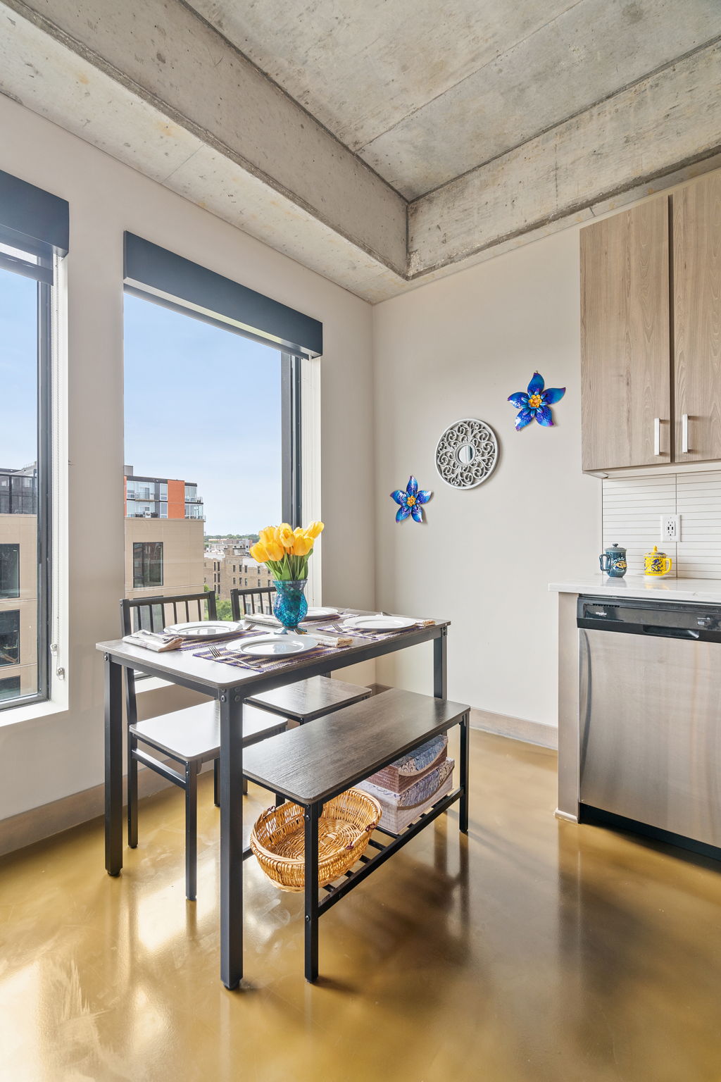 A bright and modern kitchen featuring a dining area with yellow tulips and blue decor.