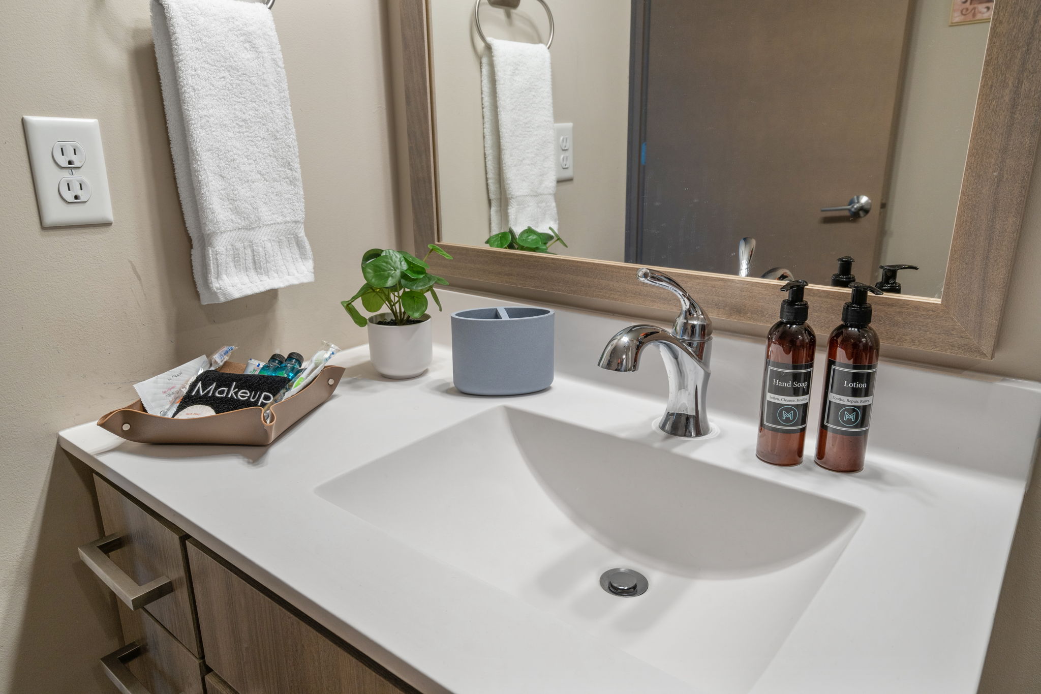 A modern bathroom countertop featuring essential items and a touch of greenery.