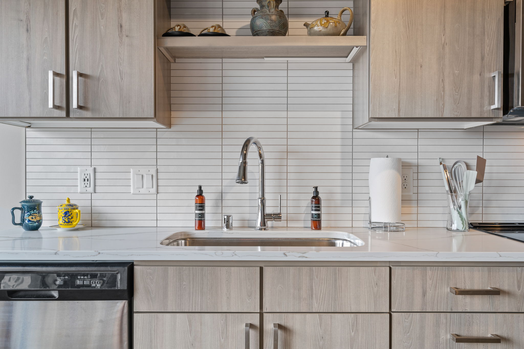 A modern kitchen sink area featuring stylish utensils and decorative dishware.