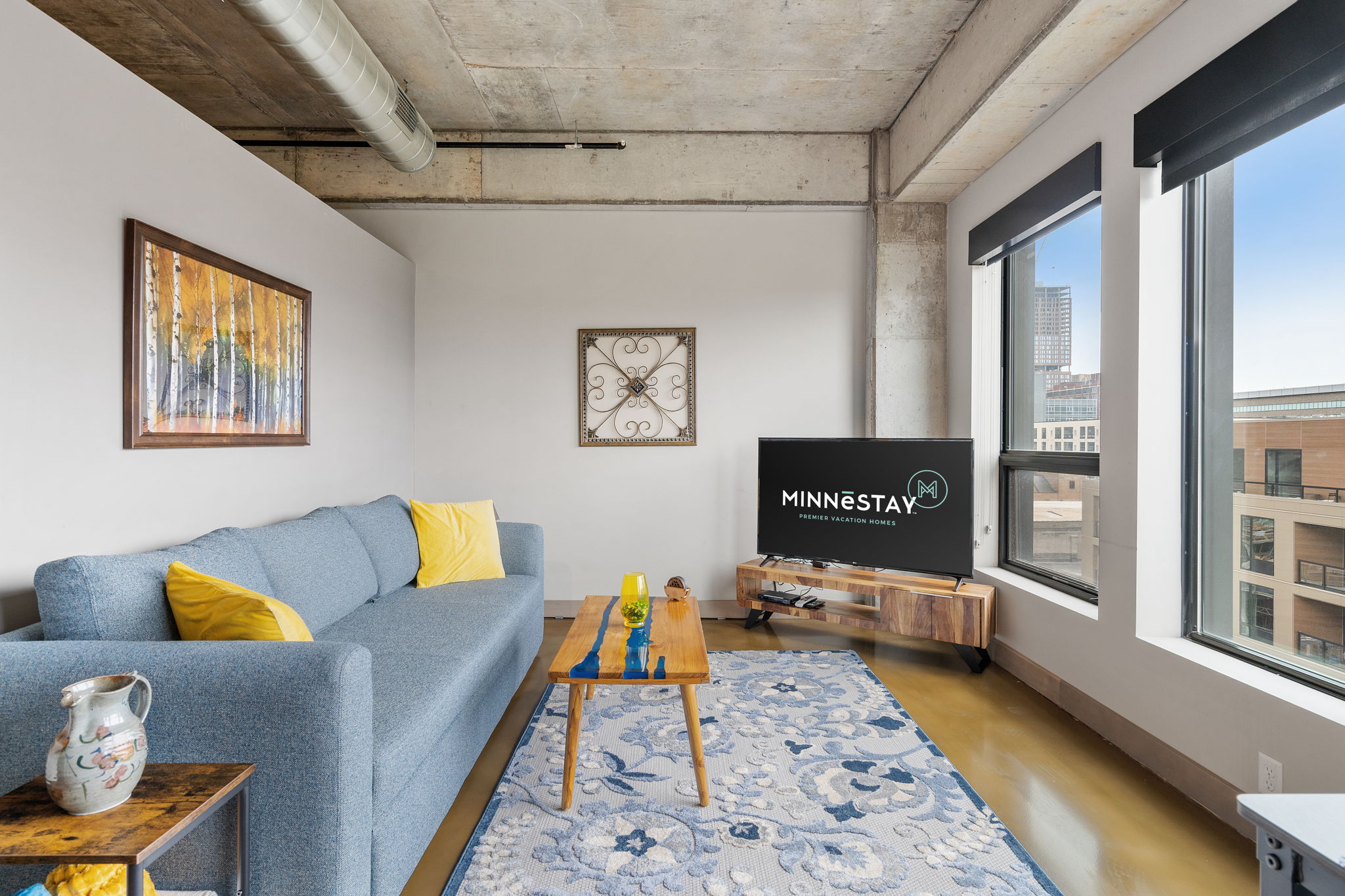 A stylish living room featuring a light blue sofa with yellow cushions and modern decor elements.