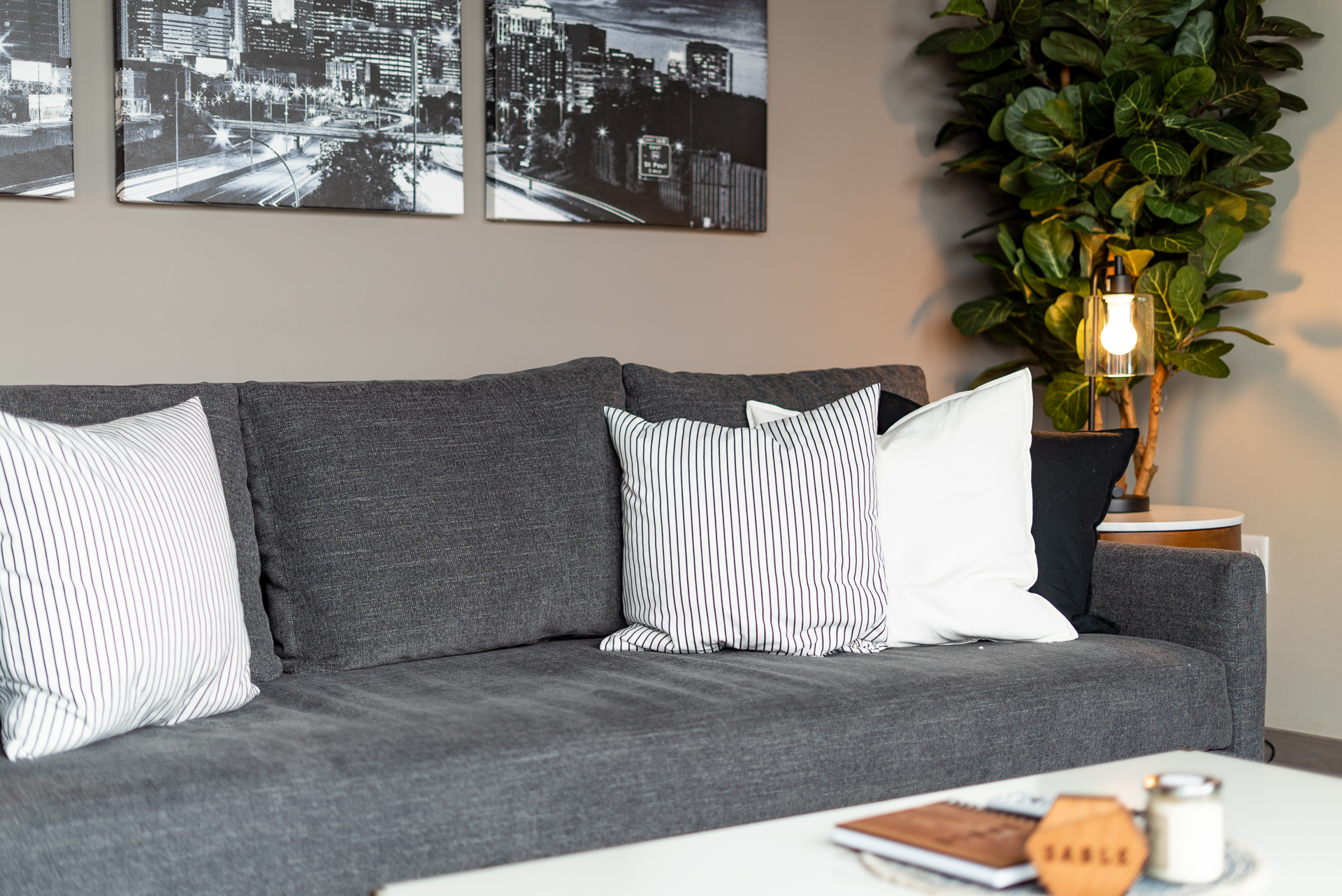 A stylish living room featuring a gray sofa with decorative pillows and urban art on the wall.