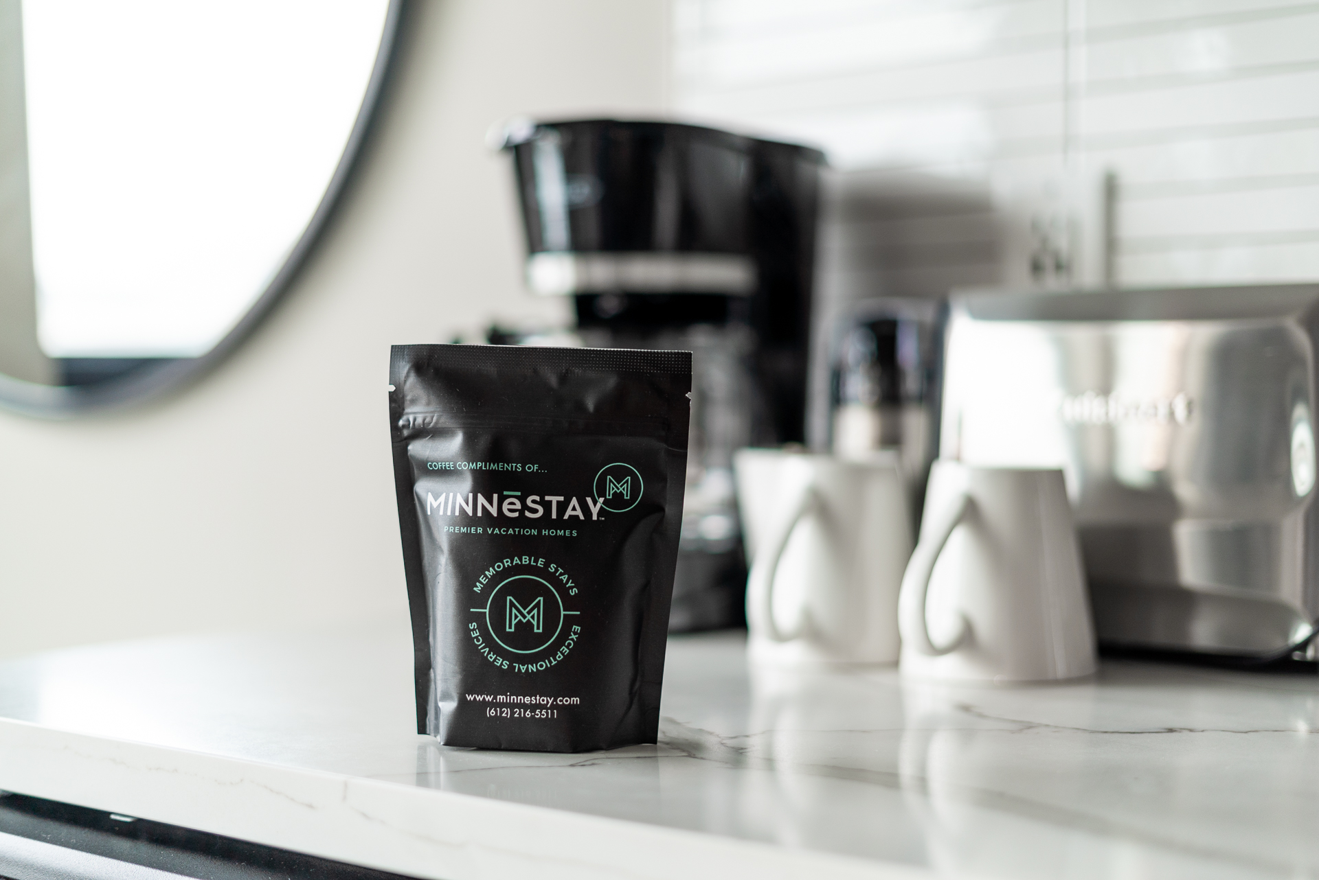 A stylish black coffee bag from MINNESTAY on a white marble countertop, complemented by modern kitchen essentials.