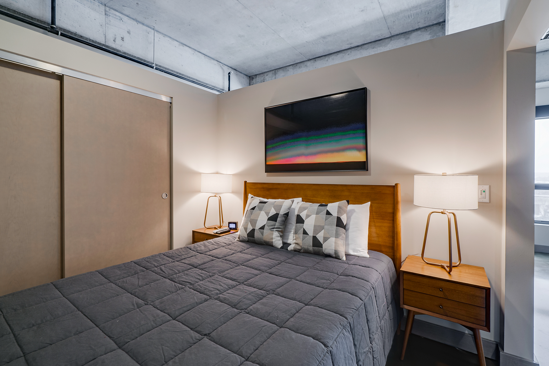 A modern bedroom with geometric accents and colorful artwork.