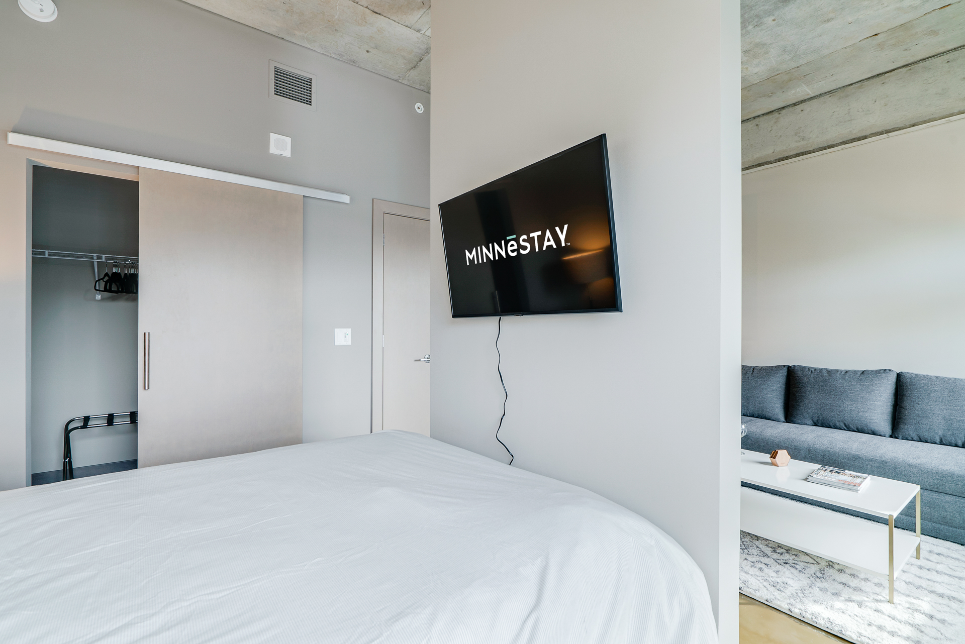 A modern bedroom featuring a cozy bed, a sleek television, and a stylish lounge area.