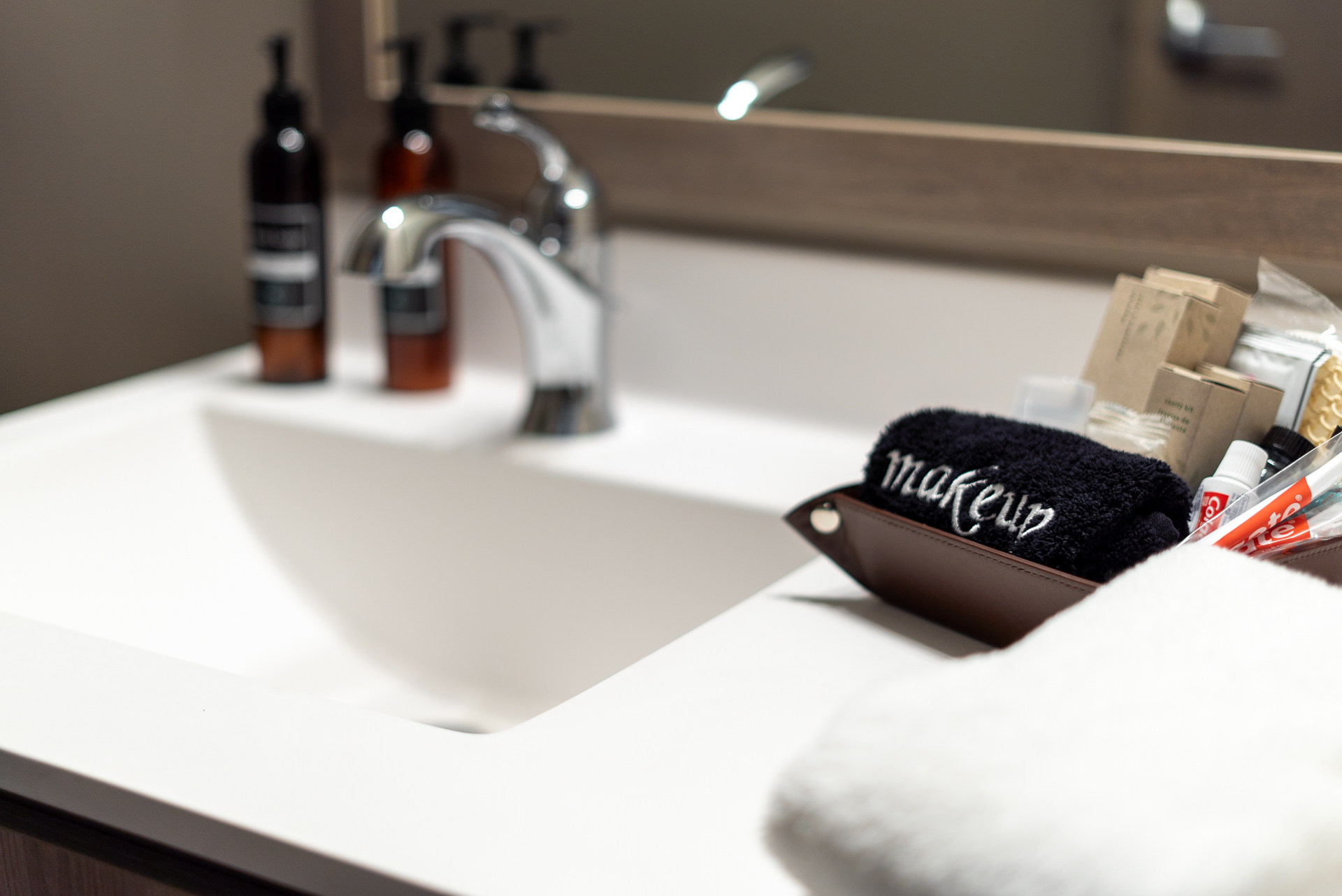 A beautifully organized bathroom sink area featuring grooming products and a makeup towel.
