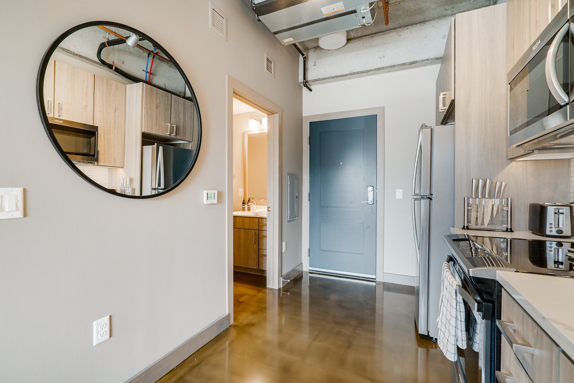 Sleek modern kitchen with circular mirror and polished floors.
