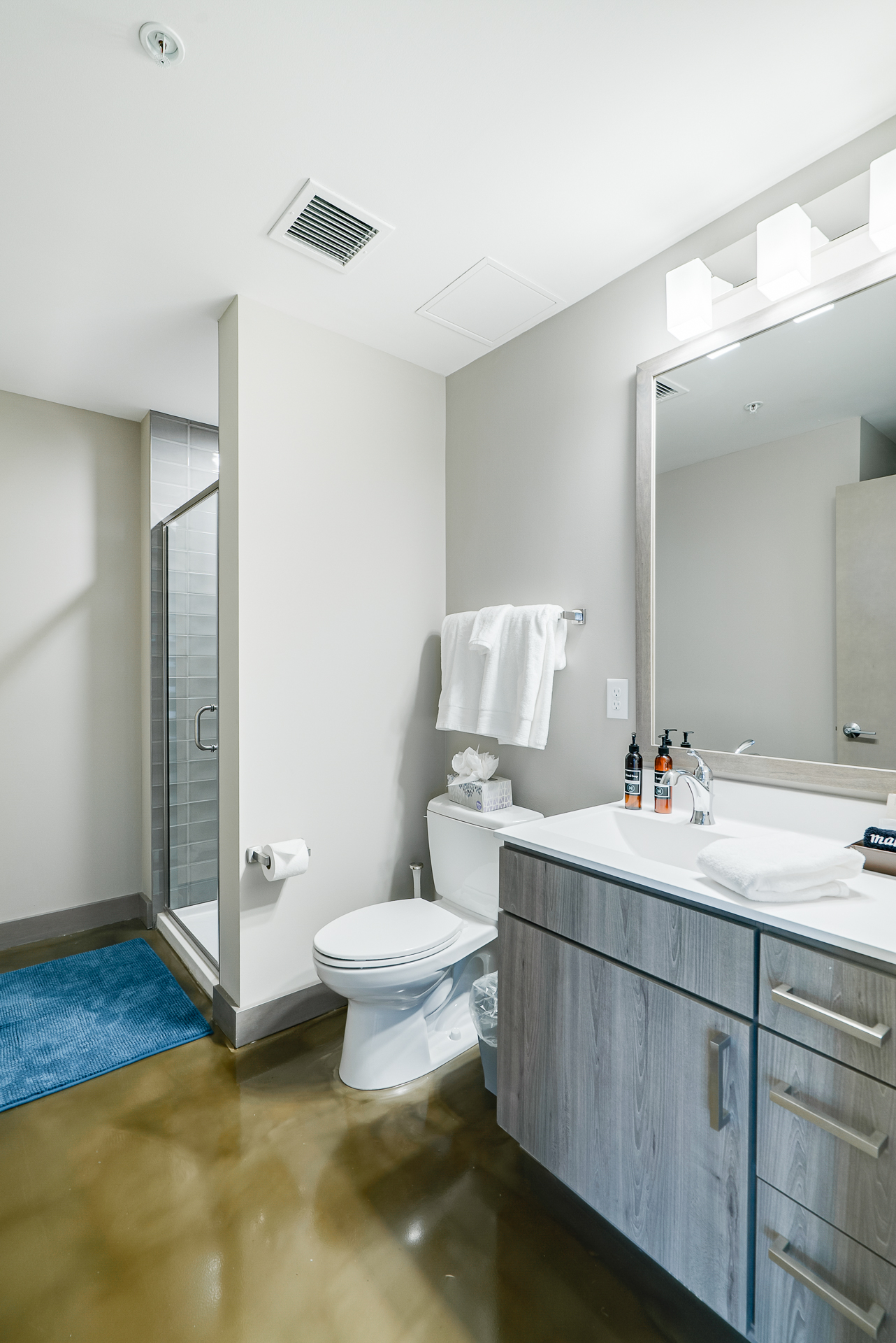 A modern, clean bathroom featuring a sleek vanity and a glass shower.