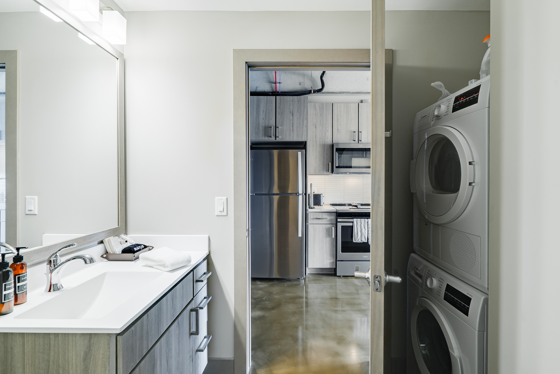 A modern bathroom leading to a stylish kitchen and laundry area.