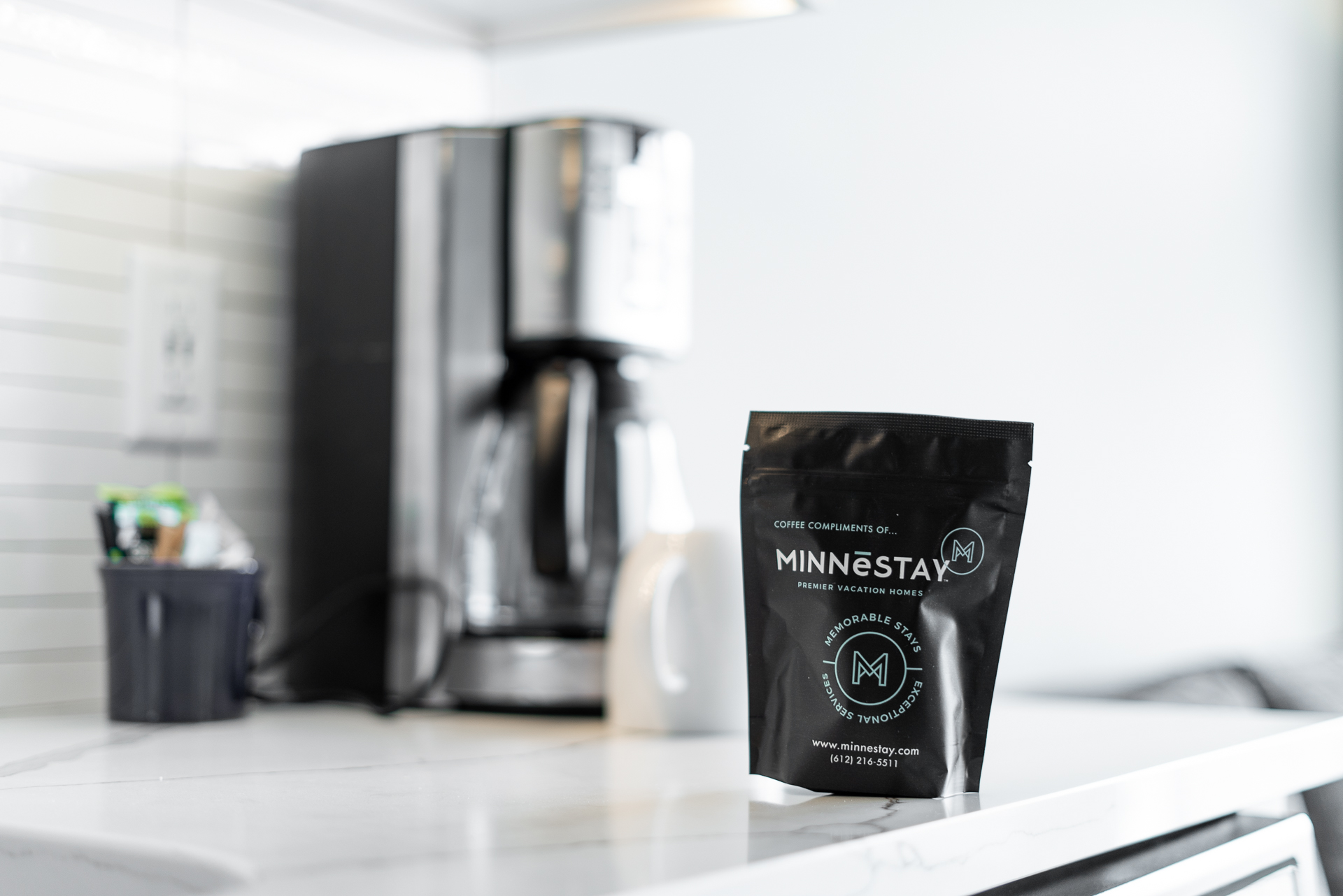 A sleek coffee packet from MINNESTAY graces a modern kitchen countertop next to a coffee maker.