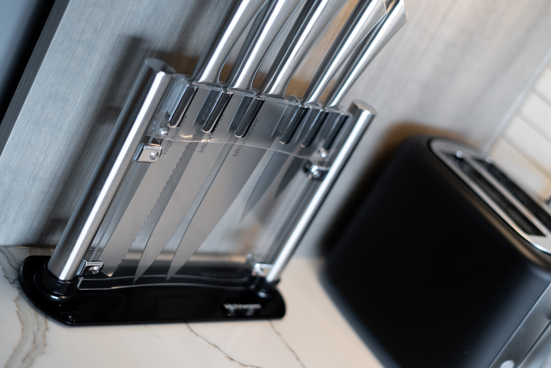 A modern knife block set with stainless steel knives on a marble countertop.