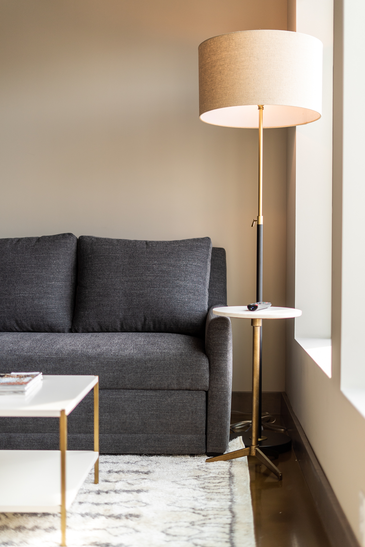 A cozy living space with a dark gray couch, stylish lamp, and contemporary side table.