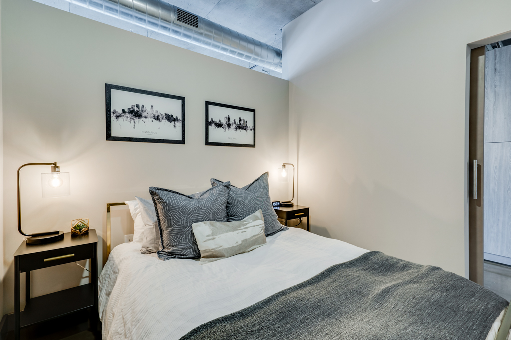 A modern and stylish bedroom featuring sleek furnishings and city skyline art.