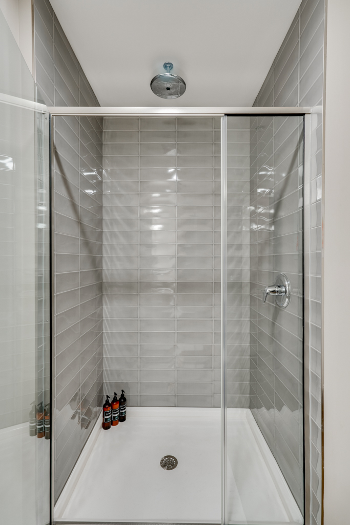 A modern and elegant shower enclosure with gray tiles and personal care products.