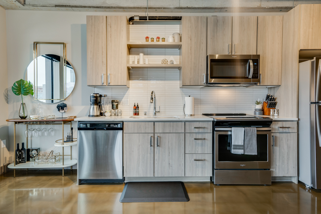 A modern kitchen featuring light wood cabinets and stainless steel appliances.