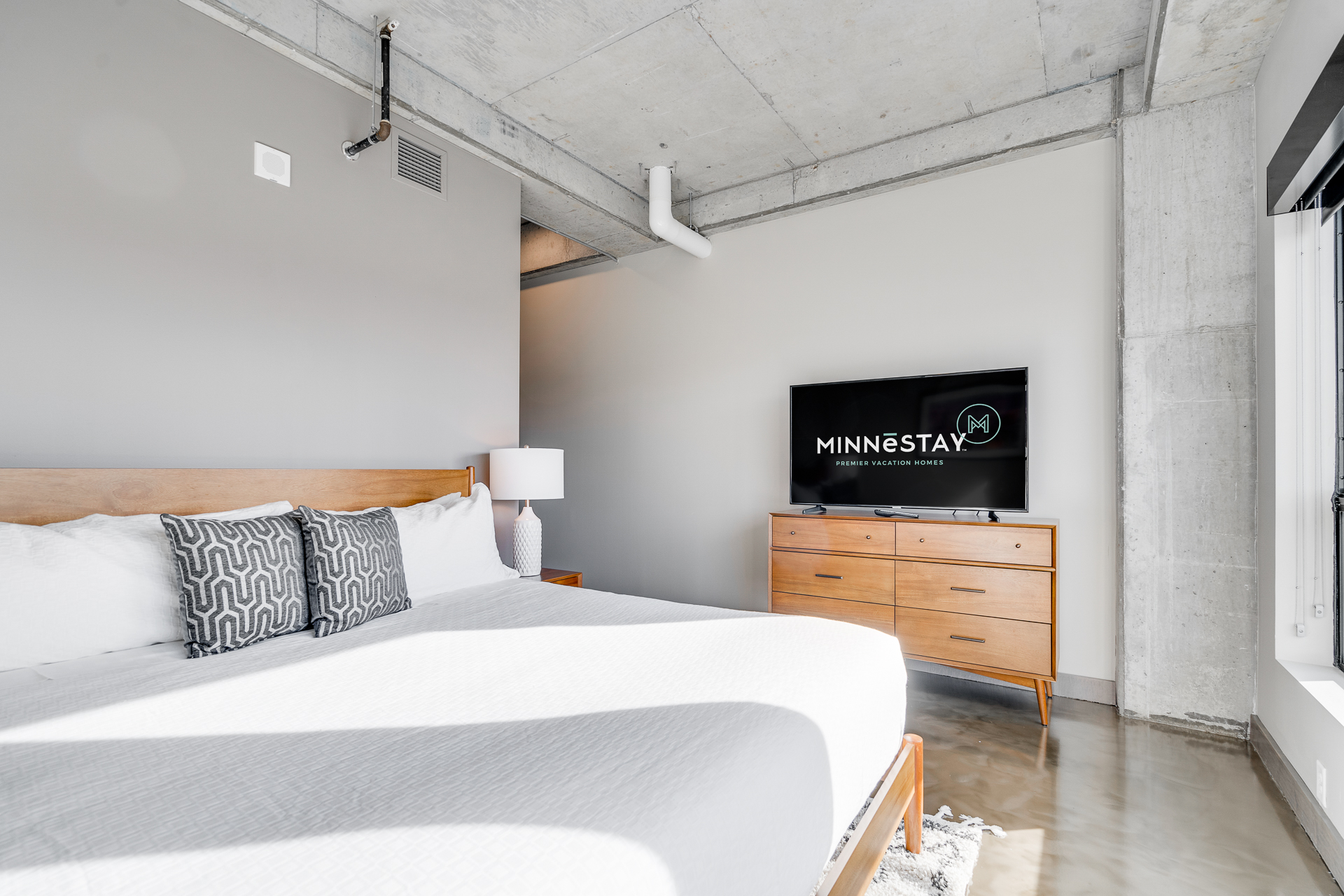 A modern bedroom featuring a queen bed and stylish interior design.