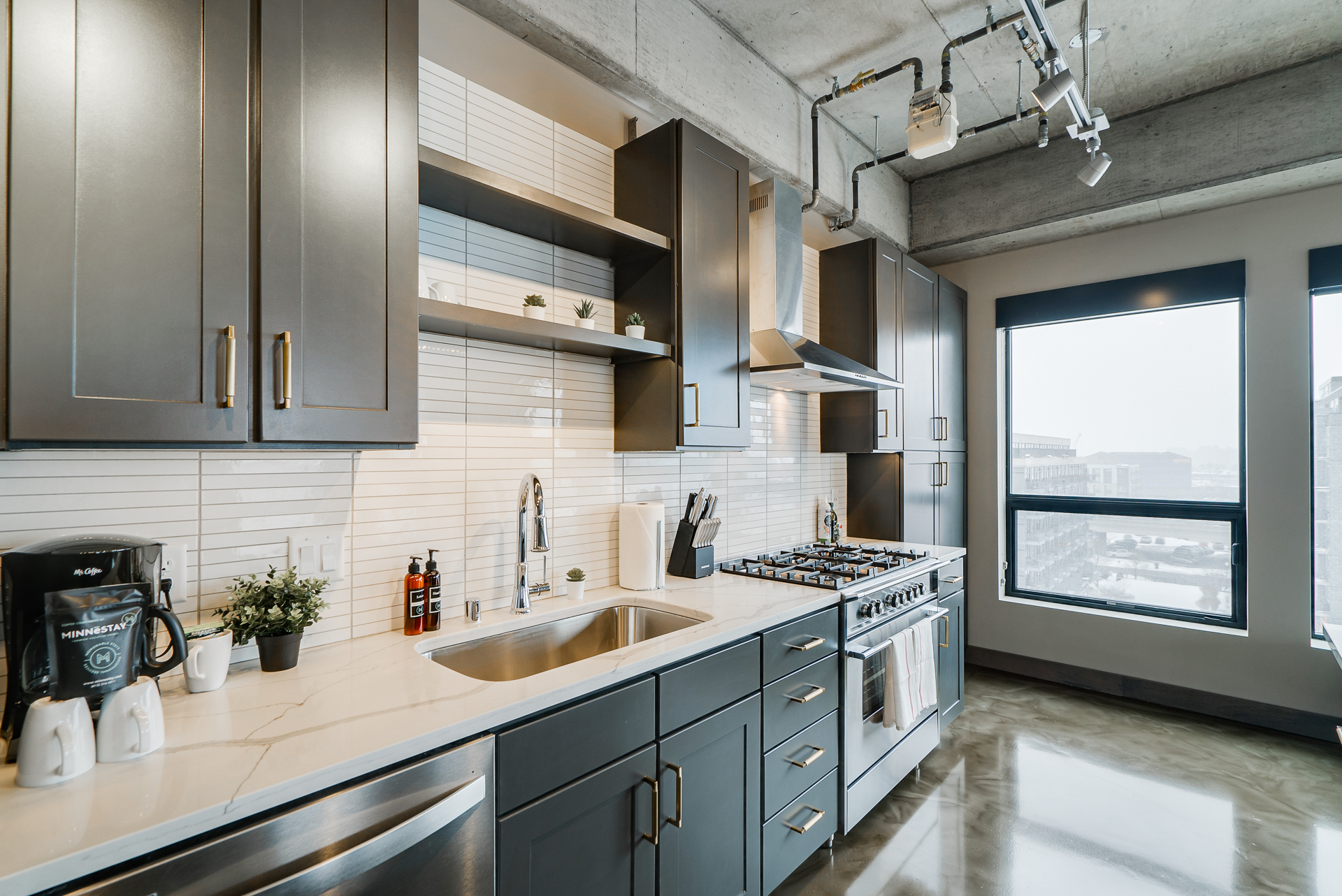 A sleek modern kitchen with dark cabinets and marble countertops.