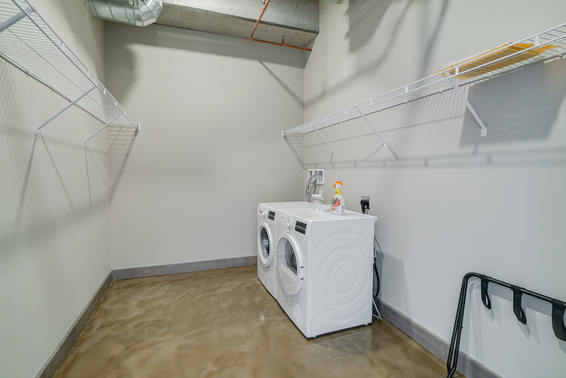 A modern and organized laundry room with white appliances and wire shelves.