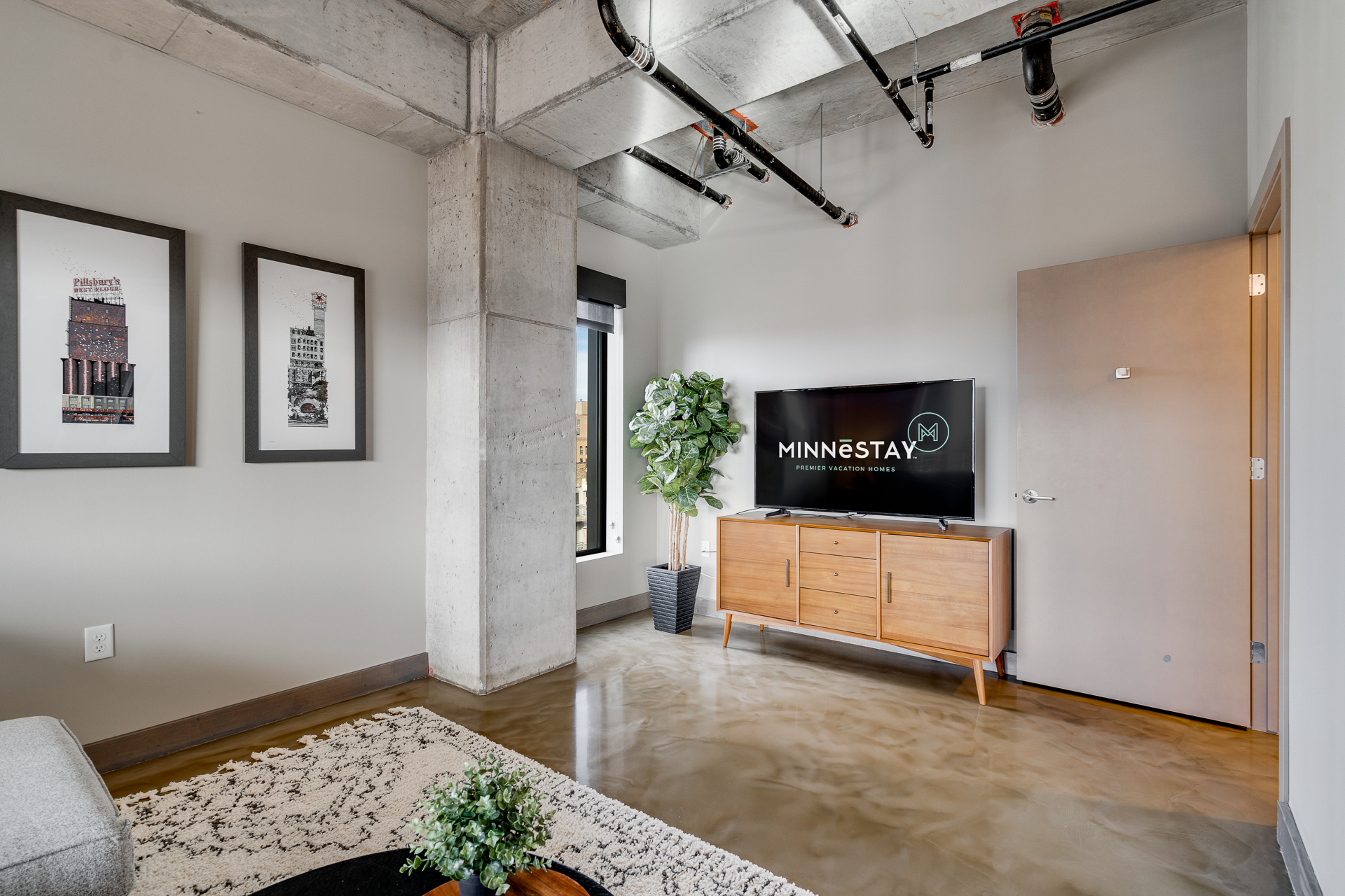 A modern living room with industrial features and mid-century furniture.