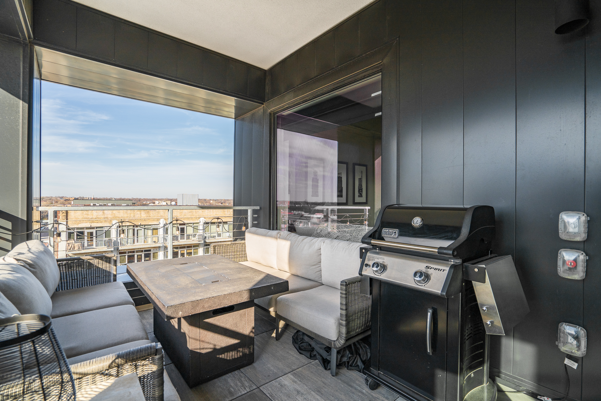 A stylish balcony featuring a cozy seating area and a grill for outdoor entertaining.
