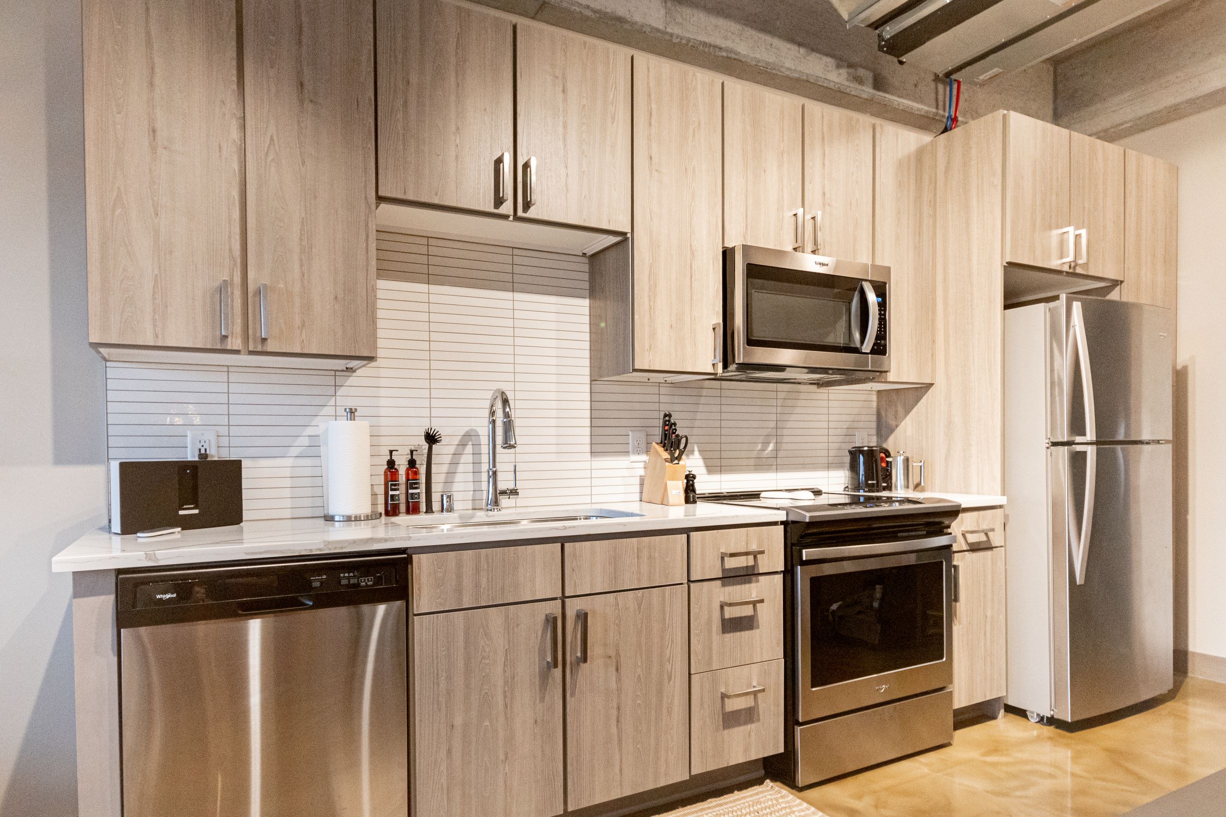 Modern kitchen design with light wood cabinetry and stainless steel appliances.