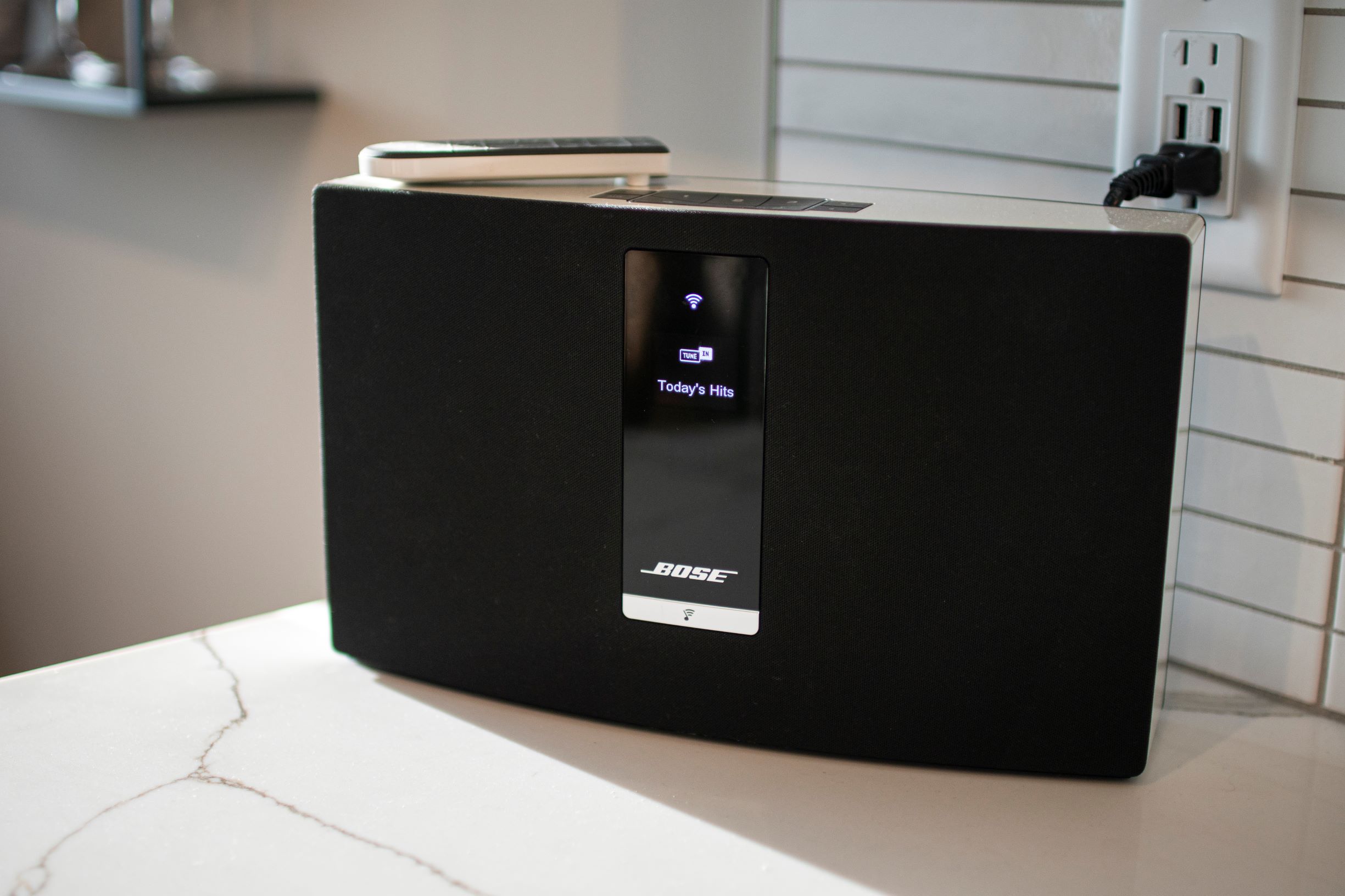 A modern Bose speaker displaying 'Today's Hits' on its screen.