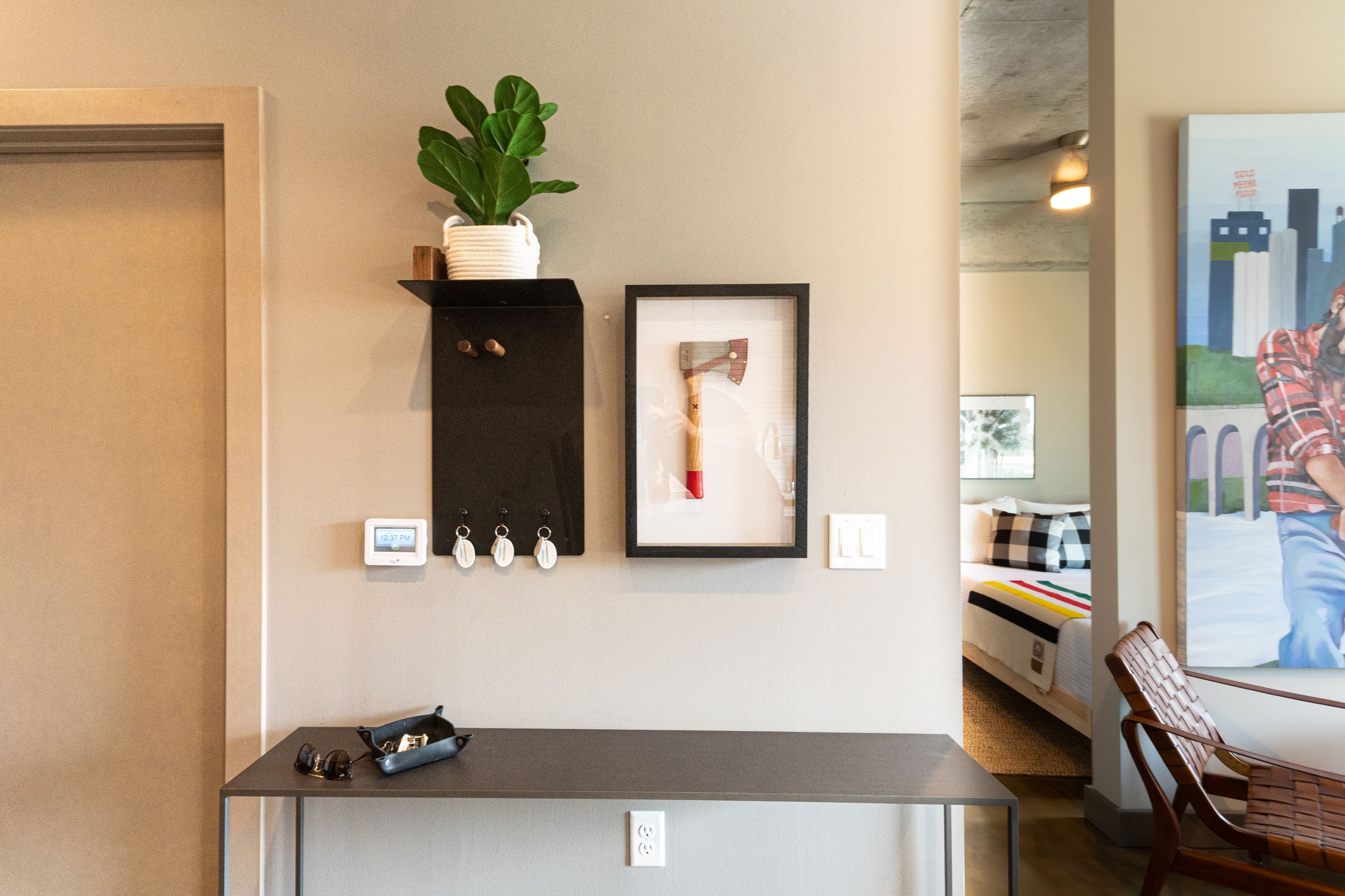 A modern entryway with stylish decor elements including a framed axe and a potted plant.