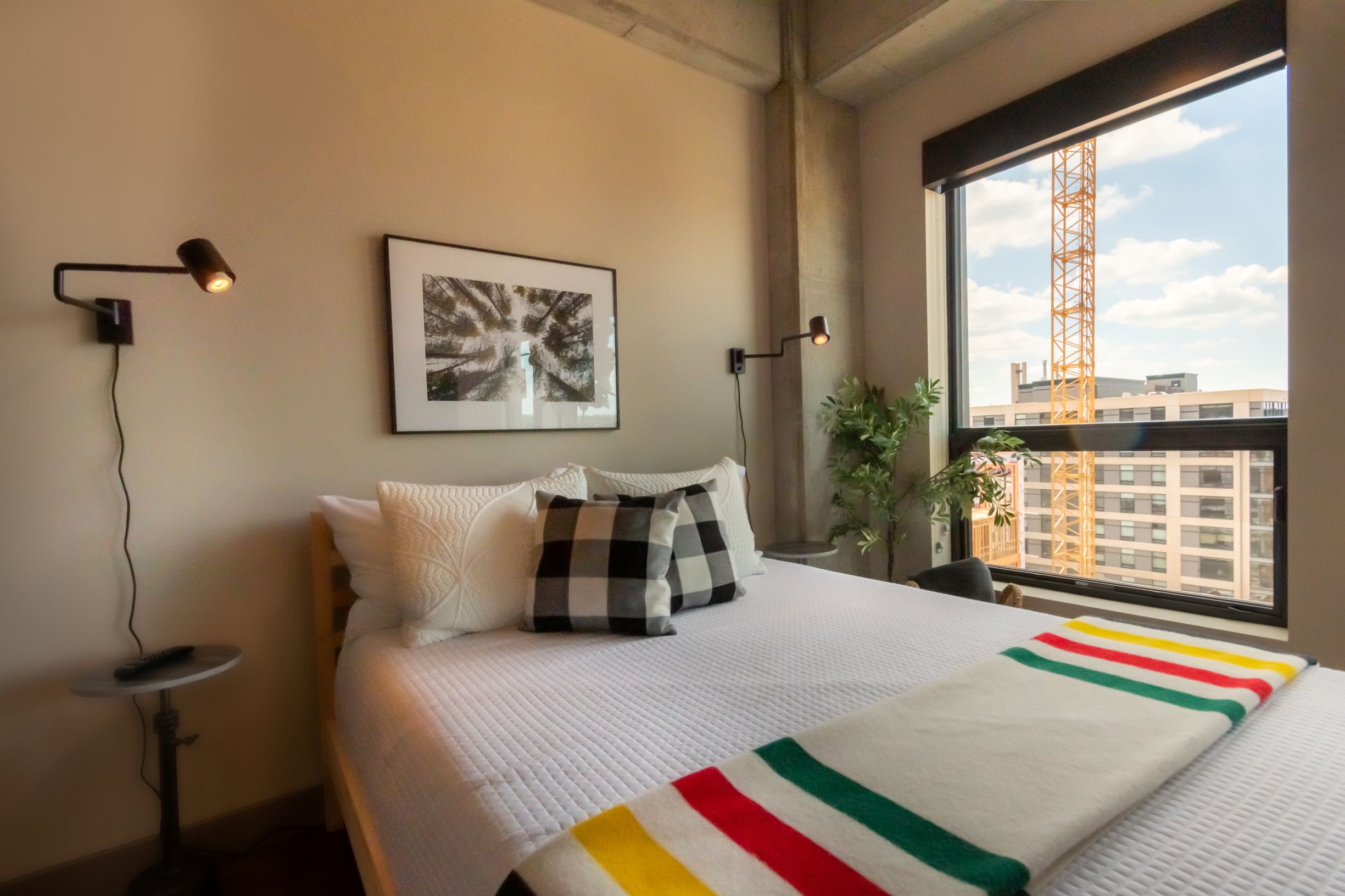 A modern bedroom with cozy decor and a view of urban construction.