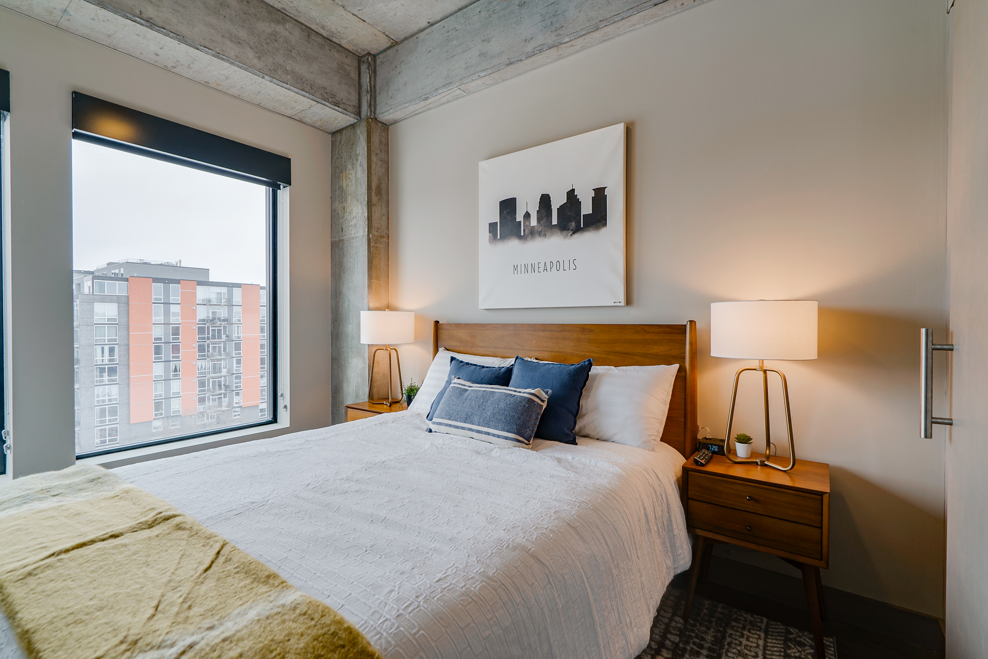 A modern bedroom with a cozy atmosphere and a view of the Minneapolis skyline.