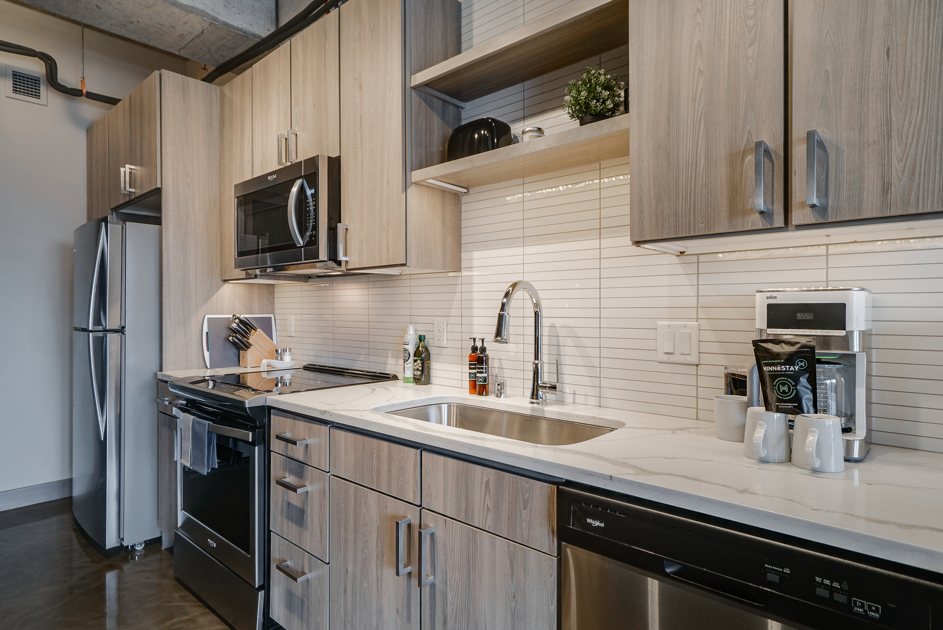 A contemporary kitchen with light wooden cabinetry and a marble countertop.