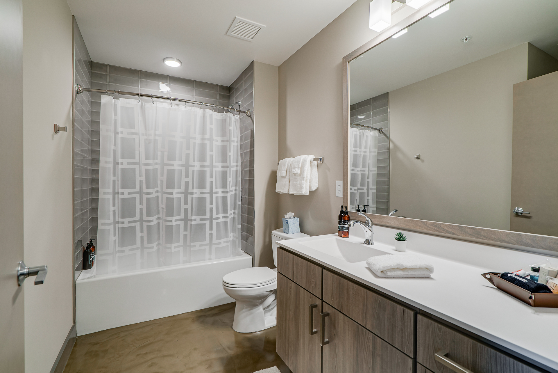 A modern and minimalist bathroom with a sleek design, featuring a shower, vanity, and contemporary decor.