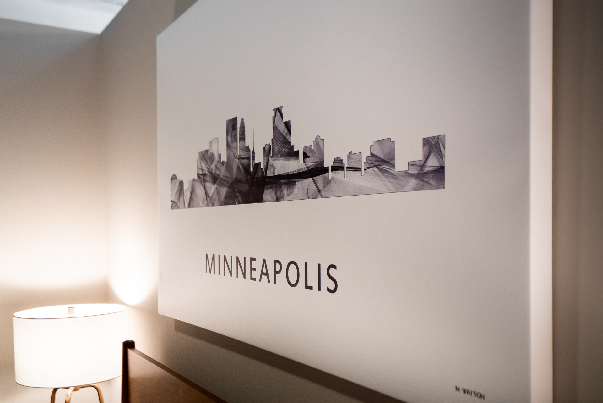 Abstract skyline art of Minneapolis displayed on a wall above a lamp.