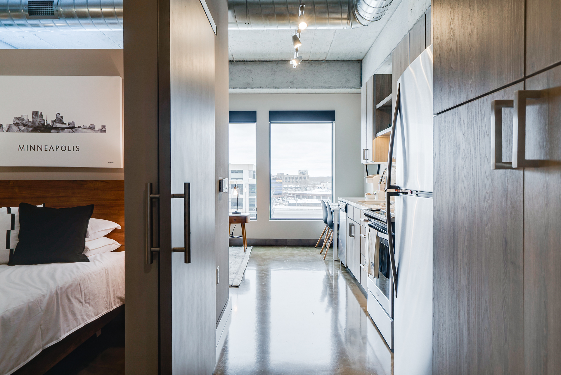 A modern studio apartment with a view of Minneapolis, featuring a sleek kitchen and cozy atmosphere.