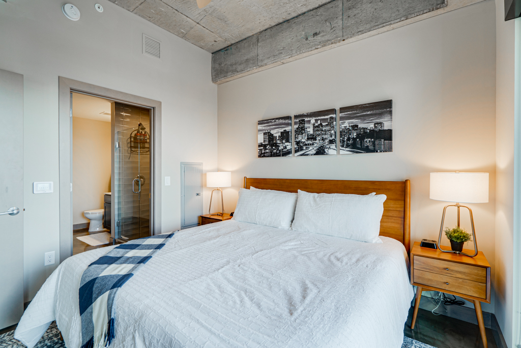 A modern bedroom featuring a large bed, decorative art, and chic furnishings.