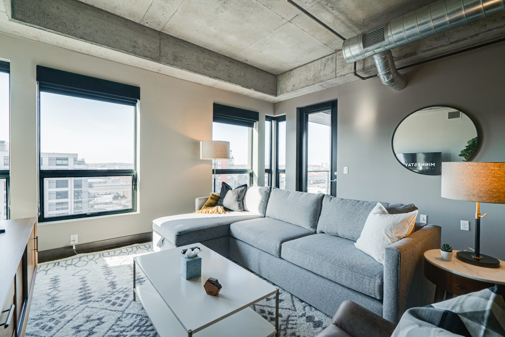 A modern living room with industrial charm and cozy furnishings overlooking an urban landscape.