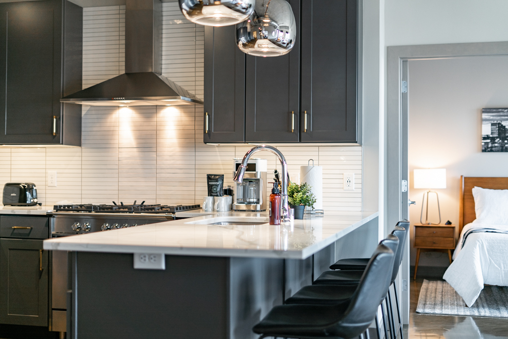 A modern kitchen featuring dark cabinetry and a sleek island with bar stools.