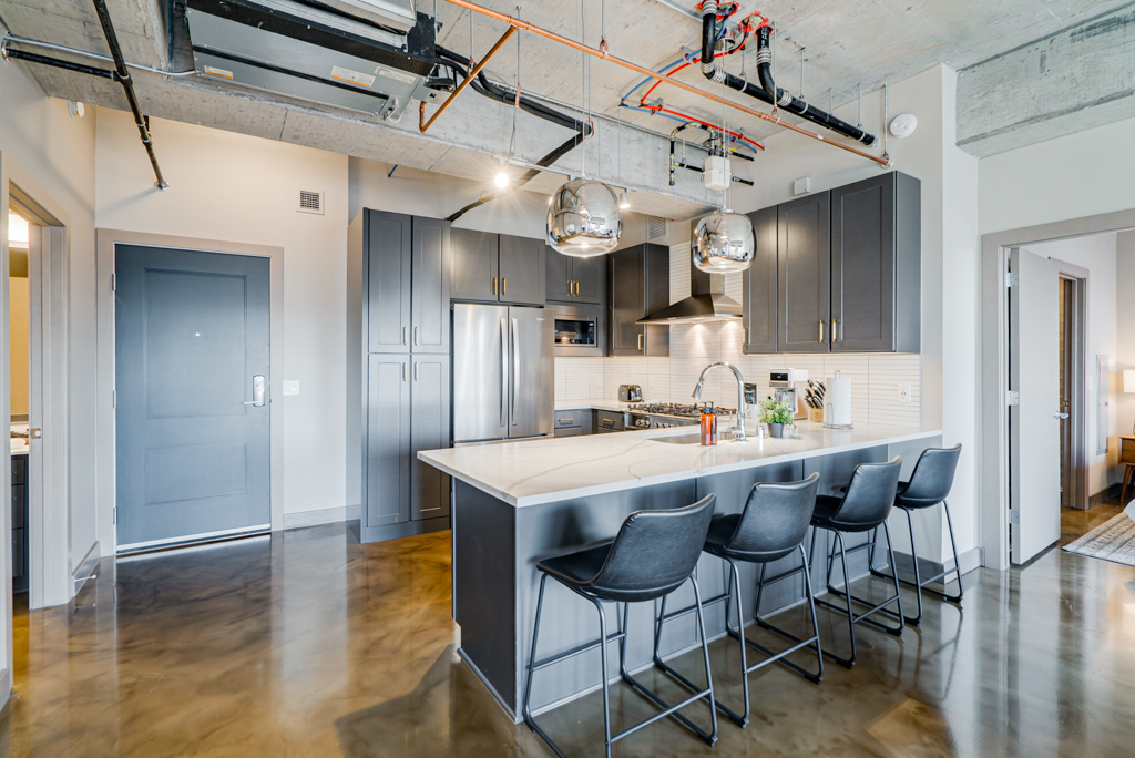 A modern kitchen with gray cabinetry and stylish pendant lighting.