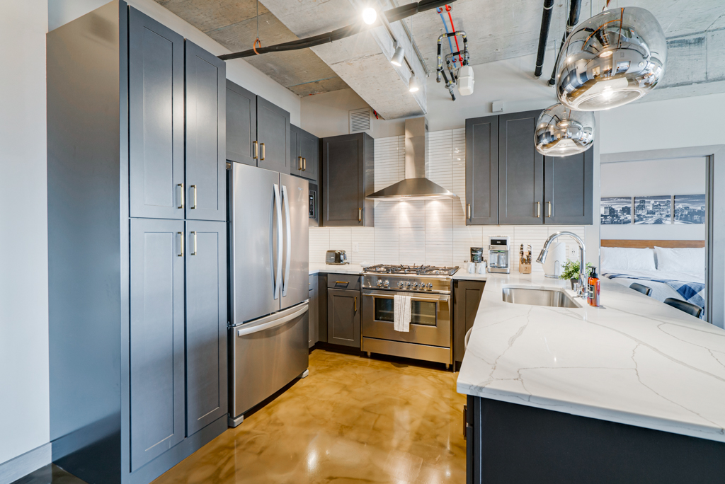 A modern kitchen with dark cabinetry and stainless steel appliances.