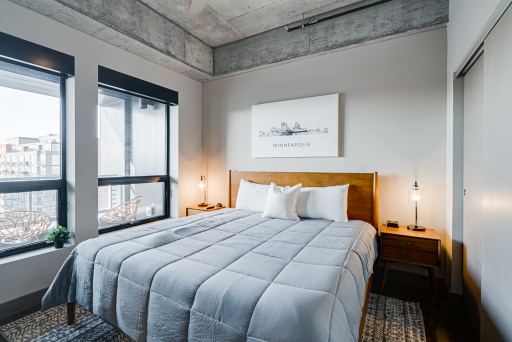 A modern bedroom with urban touches featuring a large bed and skyline artwork.
