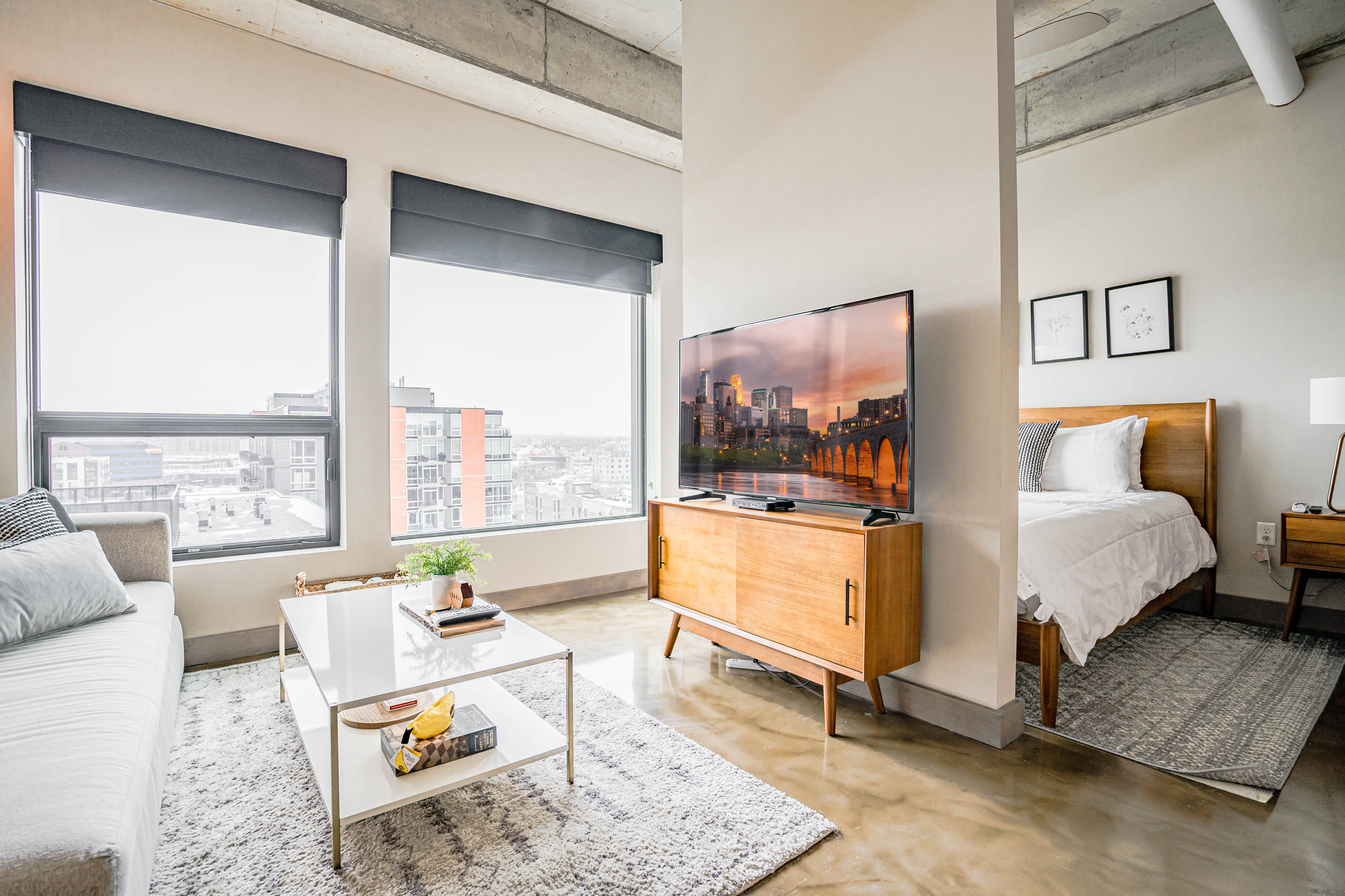 A stylish modern apartment featuring an open living space with a cozy sofa and a beautiful city view.