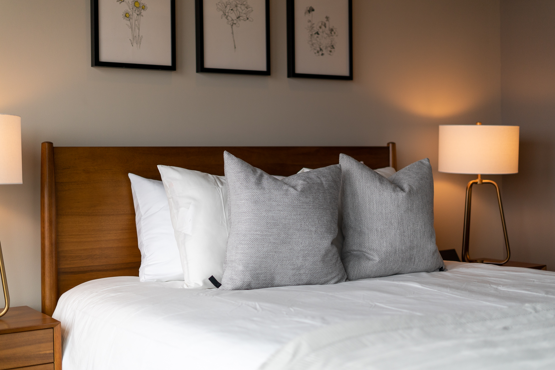 A serene bedroom with plush pillows and framed botanical art.