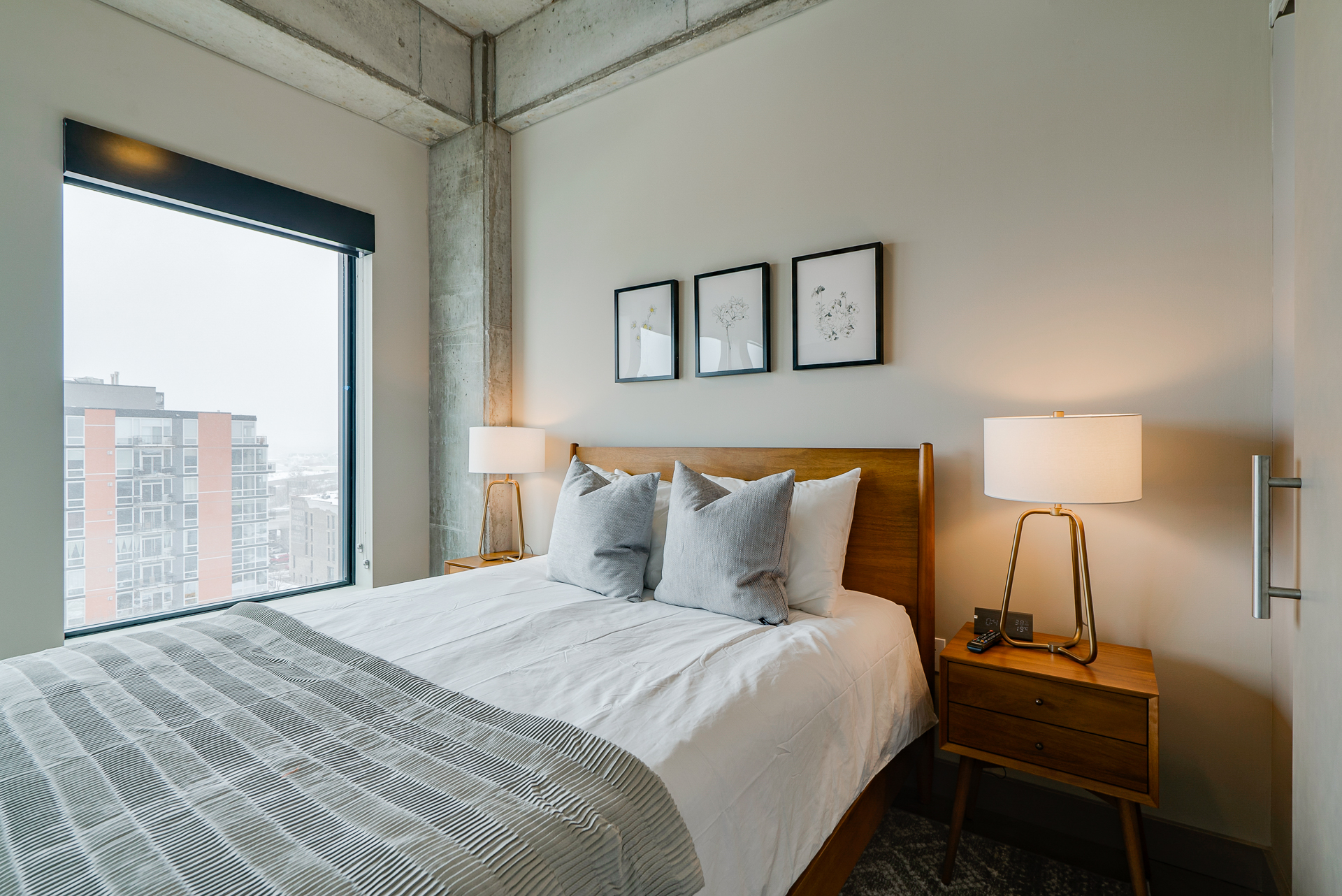 A modern bedroom with a cozy atmosphere, featuring minimalist decor and a beautiful urban view.