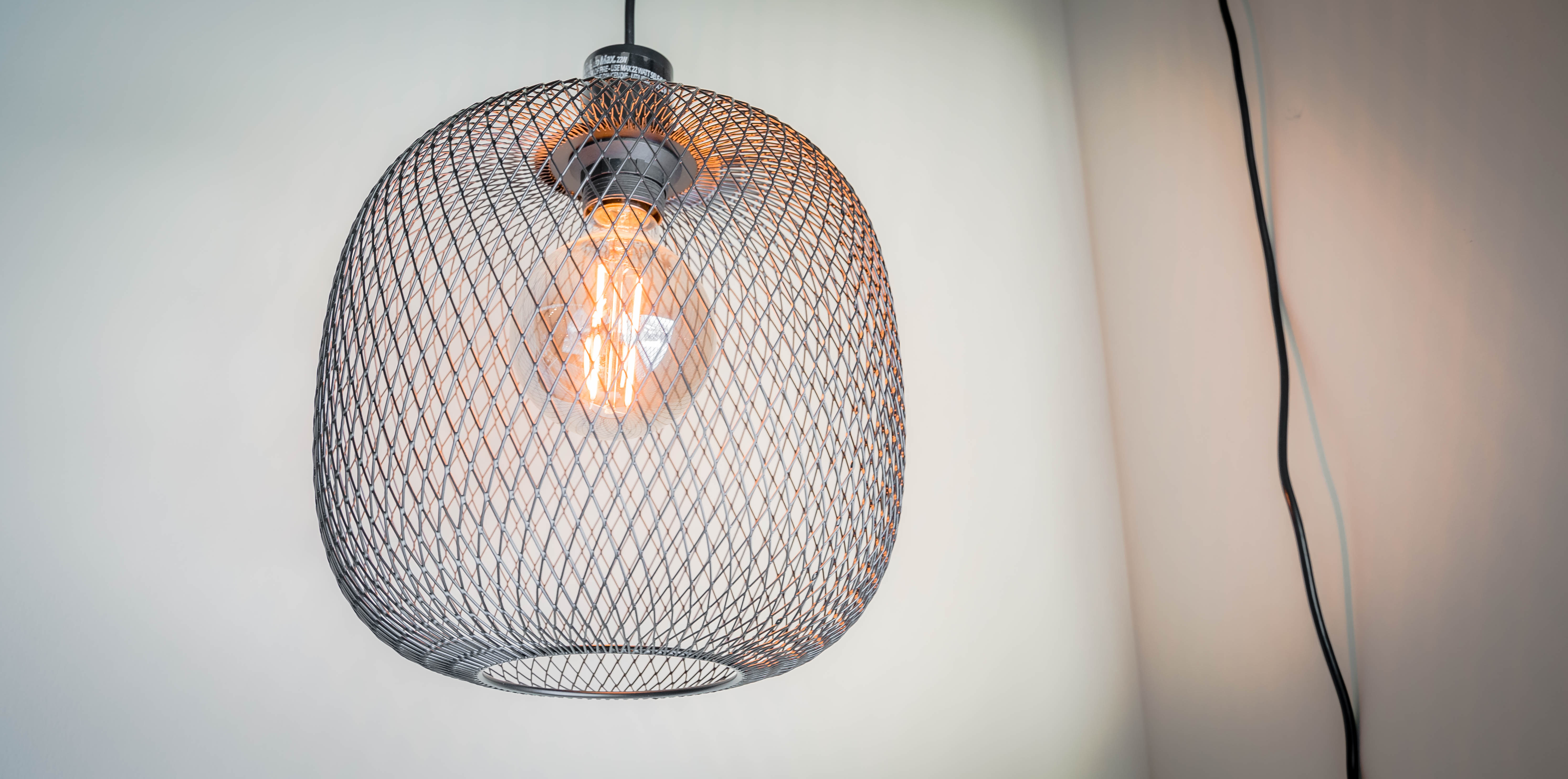 Modern pendant light fixture with a mesh design and vintage bulb.