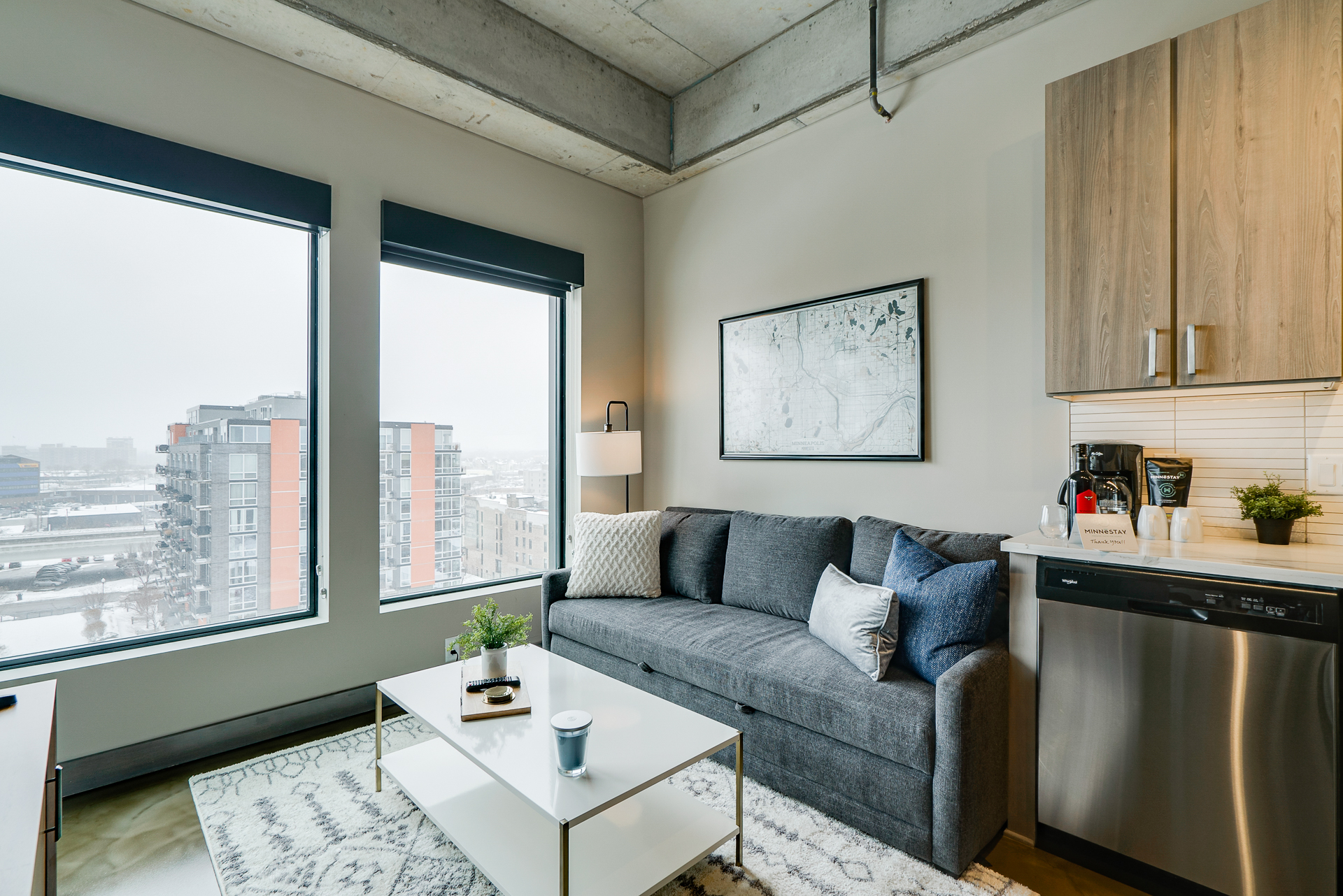 A modern and cozy living area featuring a gray sectional sofa and a stylish kitchen.