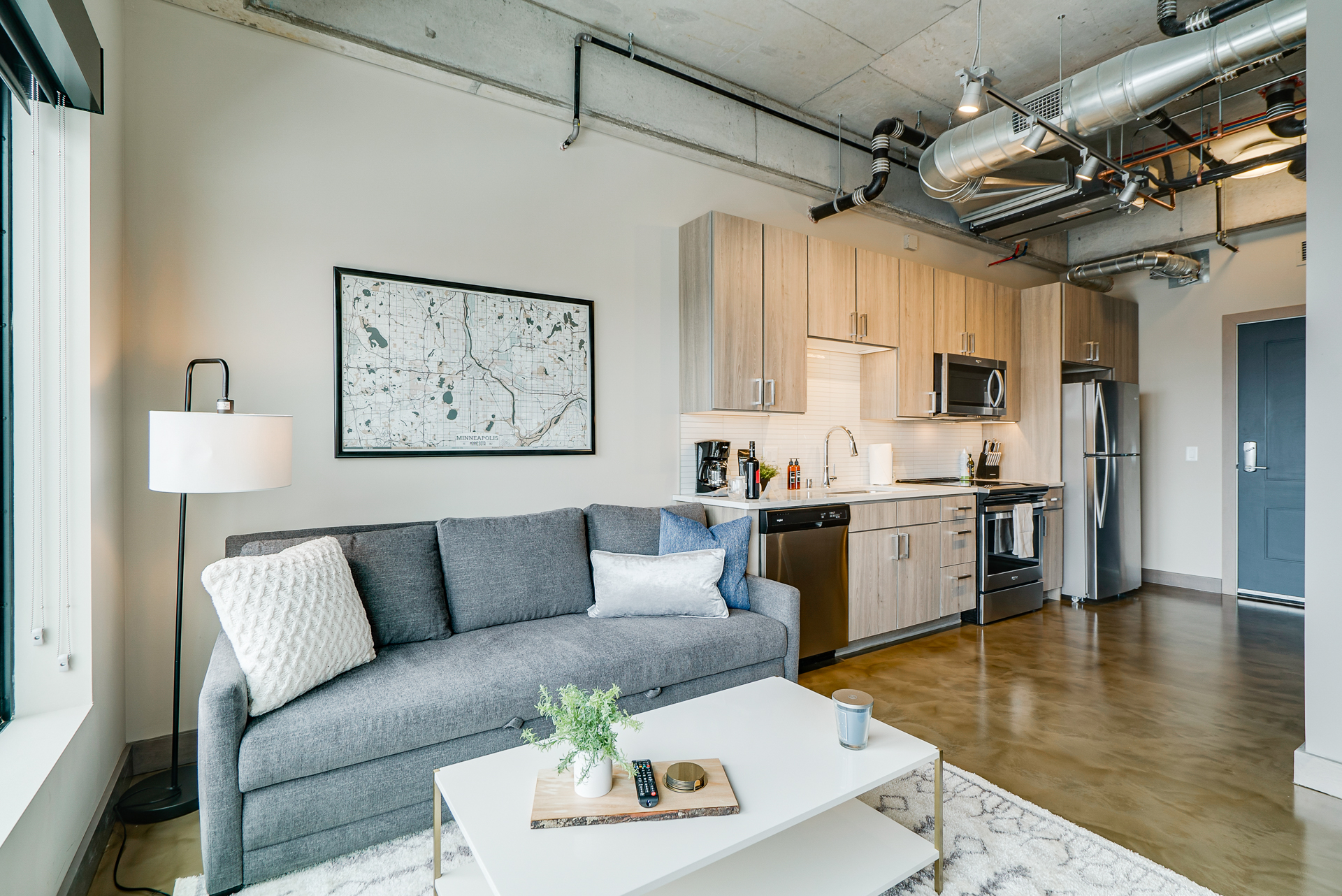 Stylish contemporary apartment interior with a gray sofa and modern kitchen setup.