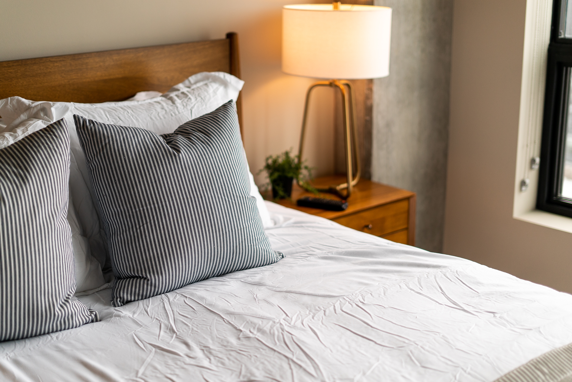 A cozy bedroom setting with stylish striped pillows and warm lighting.