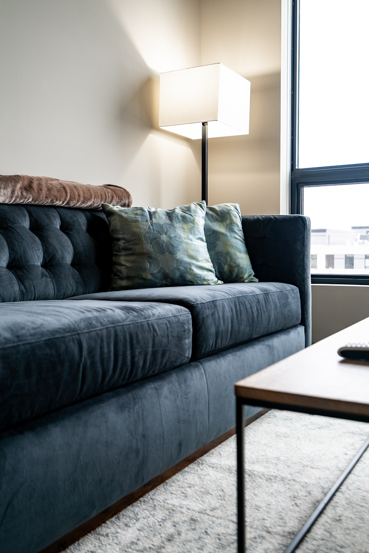 A cozy living room corner with a plush dark blue sofa and a decorative lamp.